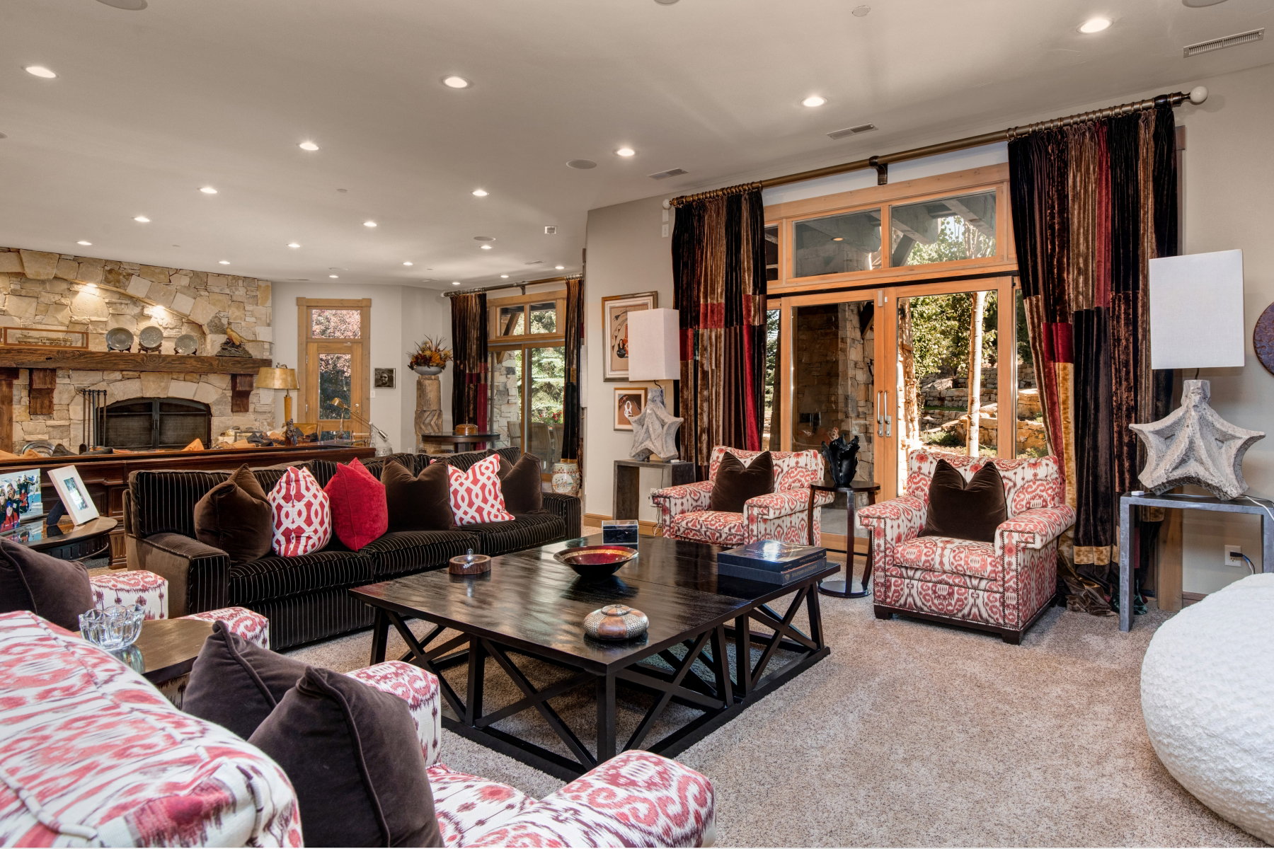 Spacious living area featuring a stone fireplace with a substantial wood mantelpiece, recessed lighting, and wood-finish French doors