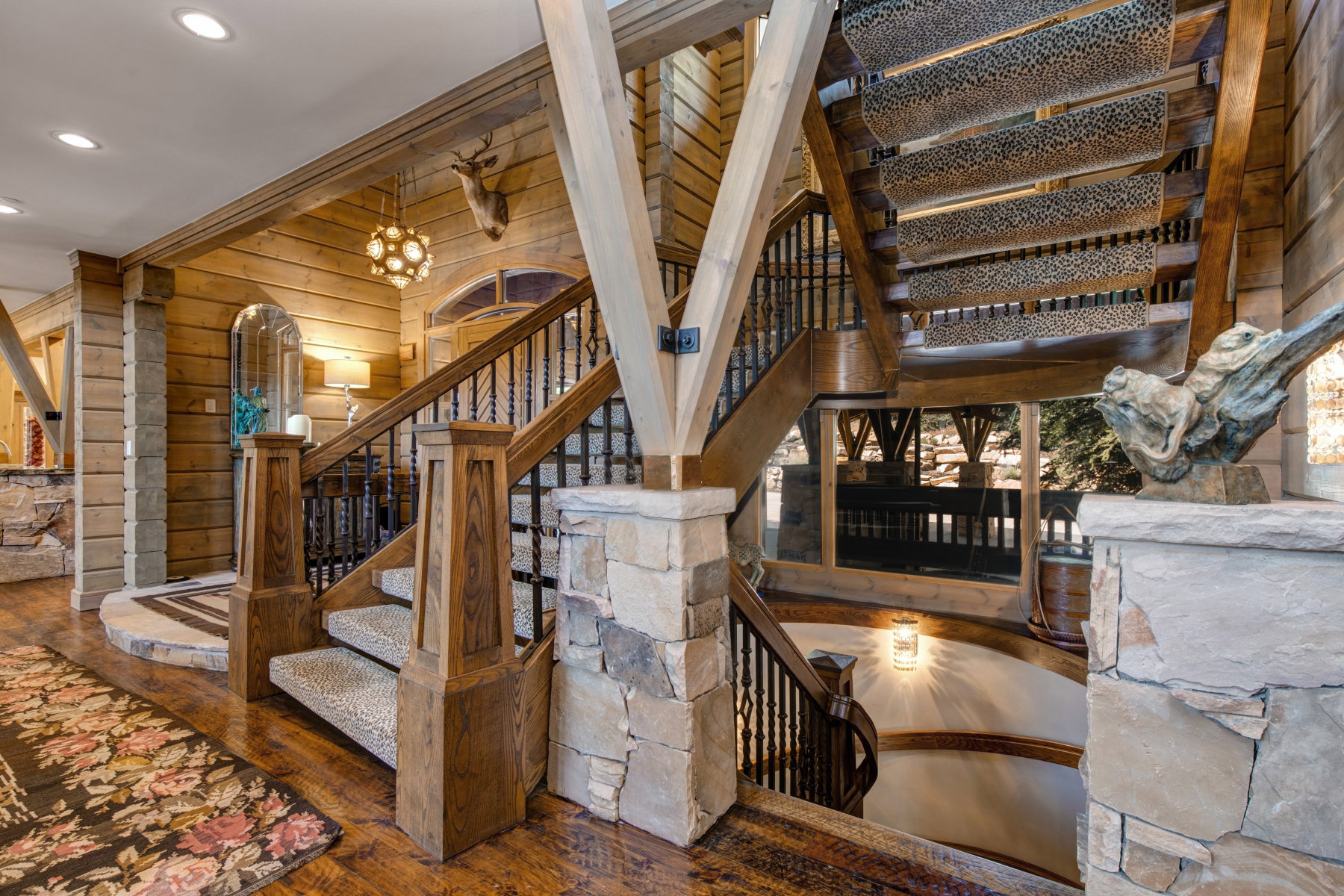 Multi-level staircase featuring wood-finish flooring, stone accents, and wrought iron balusters