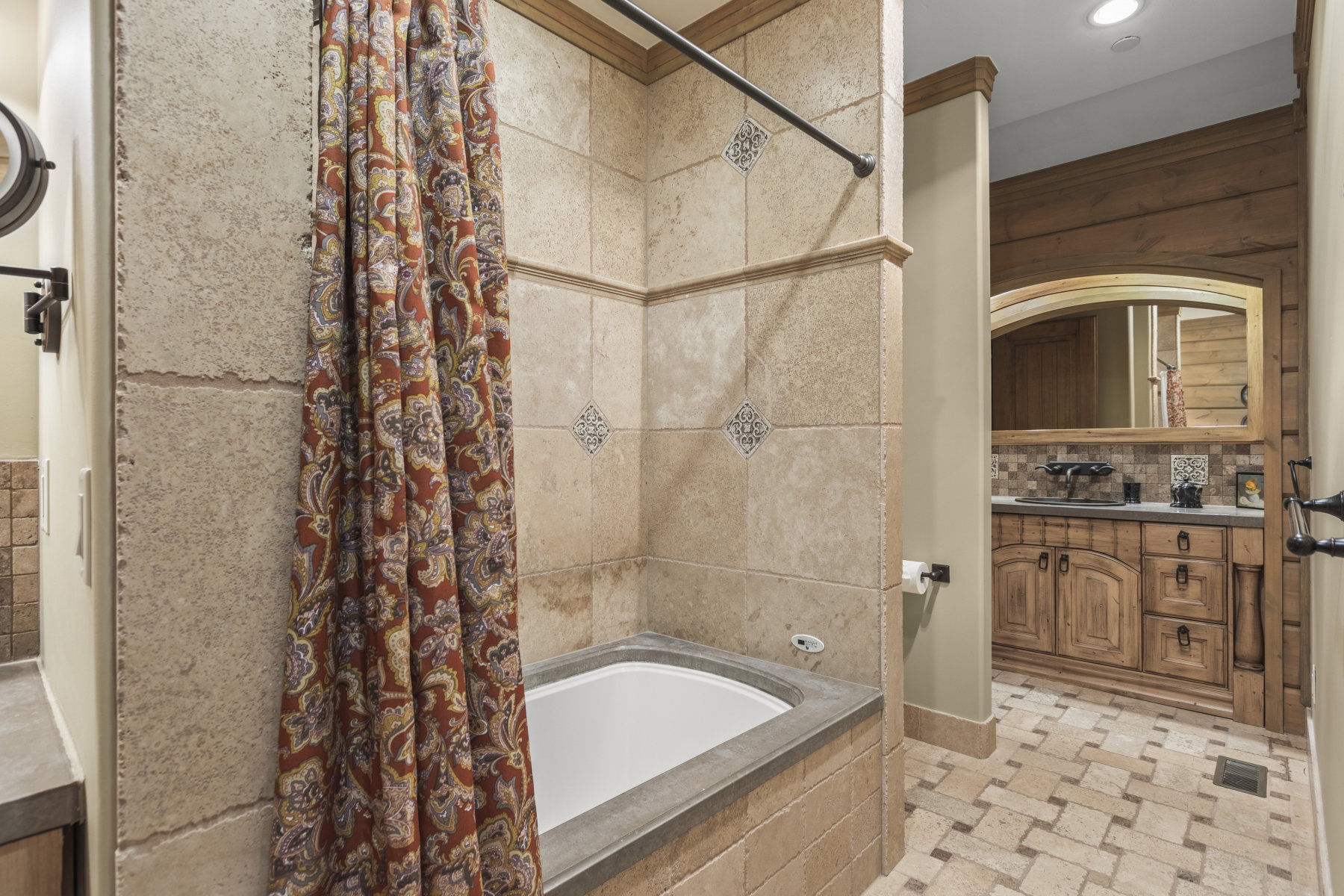 Bathroom featuring a tiled tub surround with decorative accents, an integrated bathtub, and a tiled floor