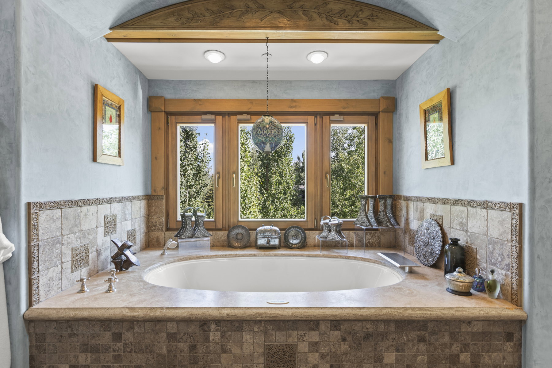 Built-in soaking tub with a stone surround, integrated deck-mounted fixtures, and a tiled base