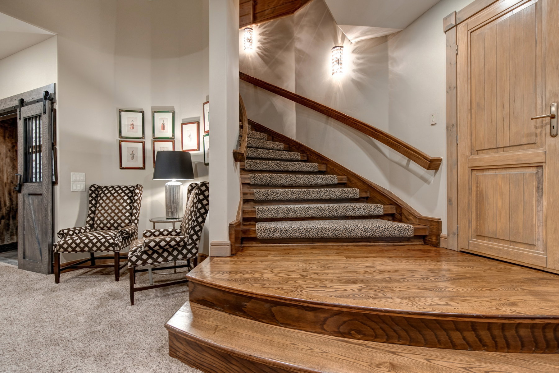Grand curved staircase with wood-finish treads and risers, featuring a patterned carpet runner and a solid wood handrail