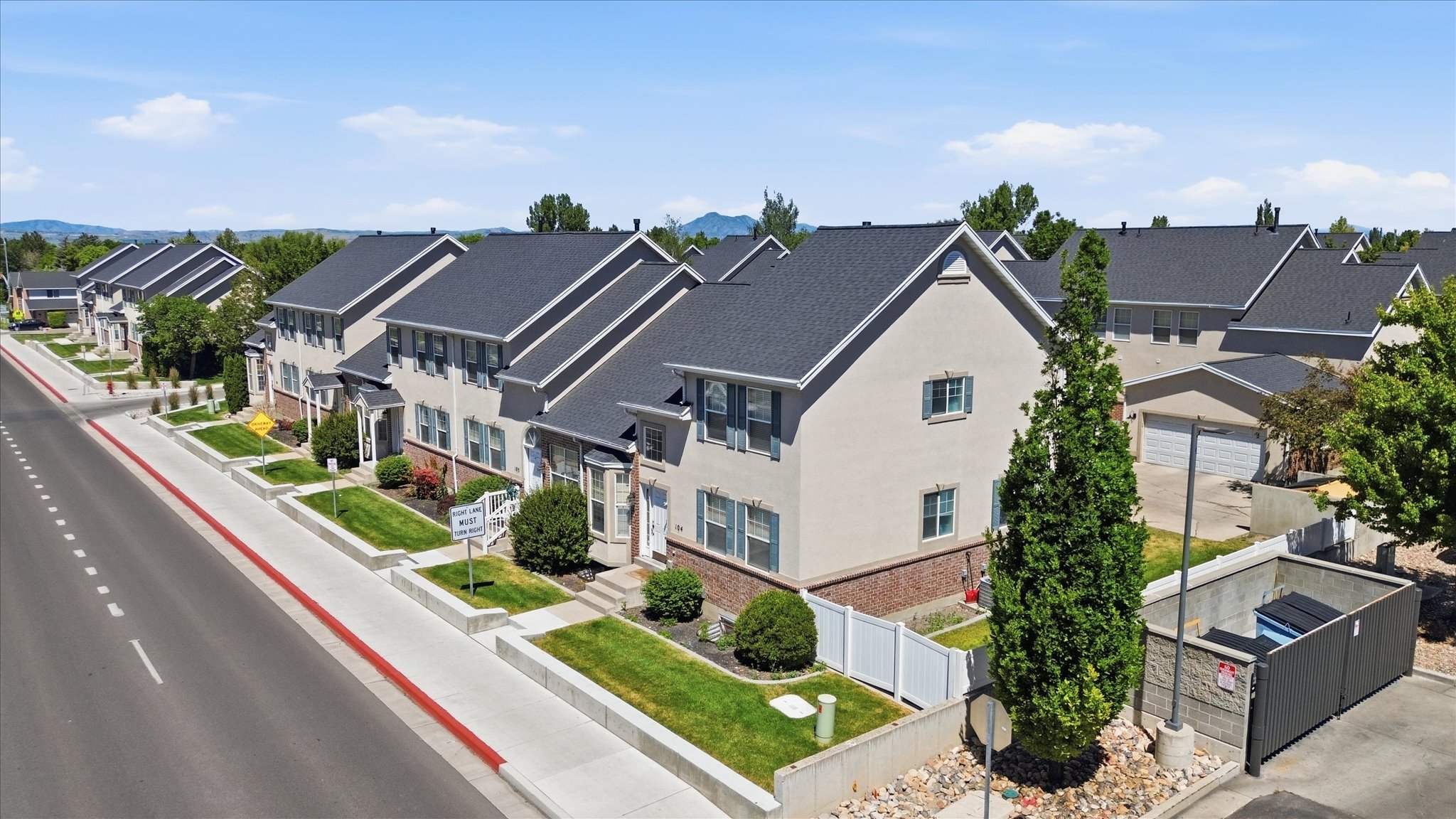 Row of townhomes featuring light-colored siding, dark shingle roofs, and brick accents