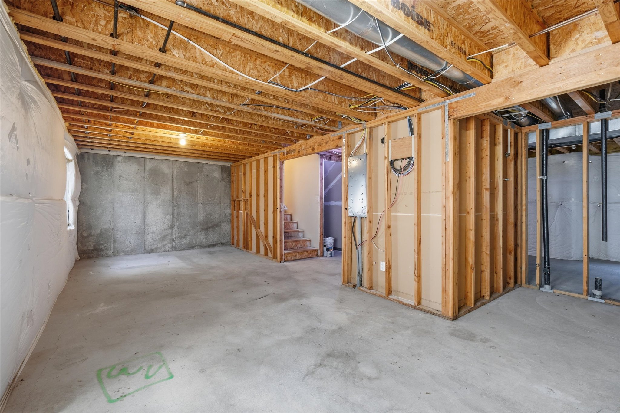 Unfinished basement featuring exposed wood joists, concrete flooring, and framed walls