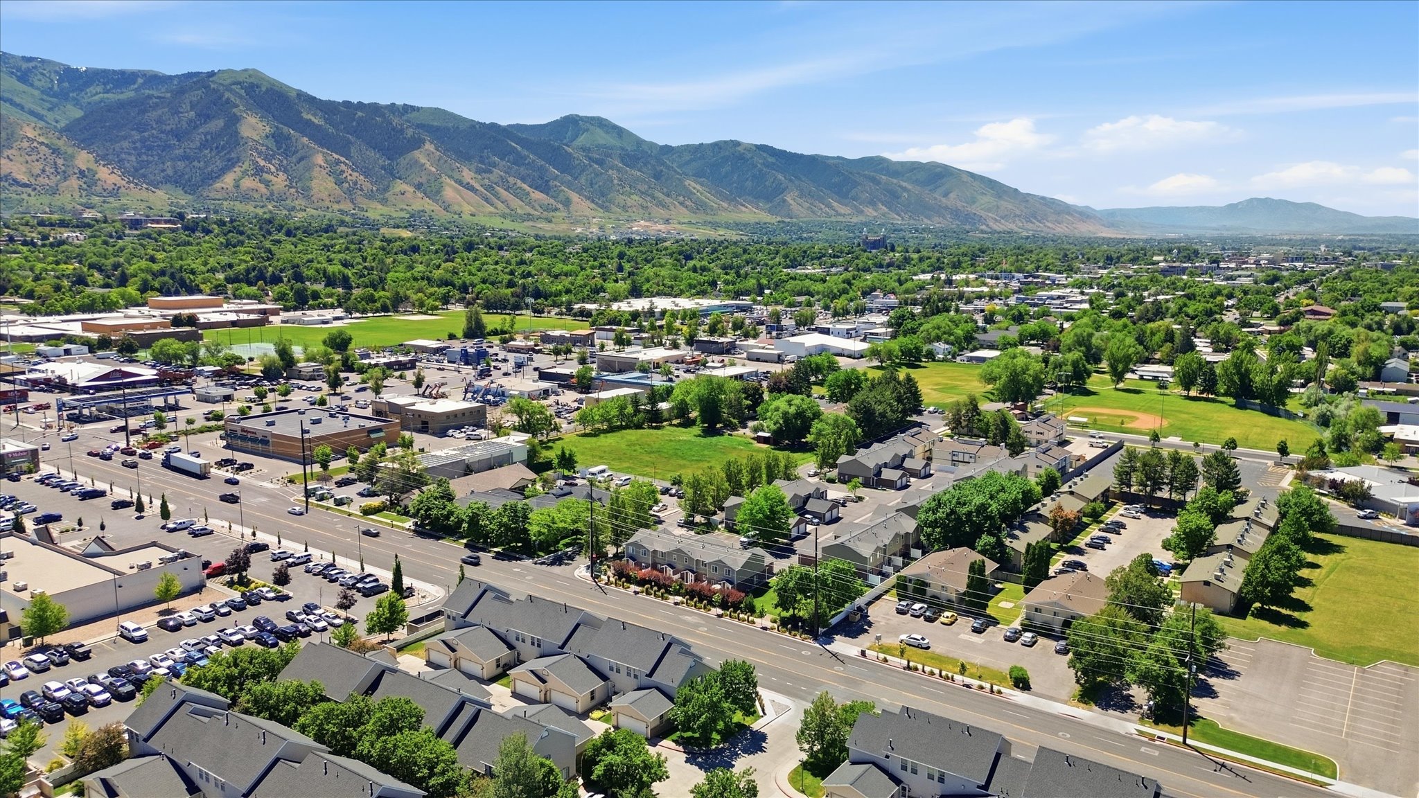 Aerial perspective showcasing a residential community with varied architectural styles, expansive green spaces, and a mountainous backdrop