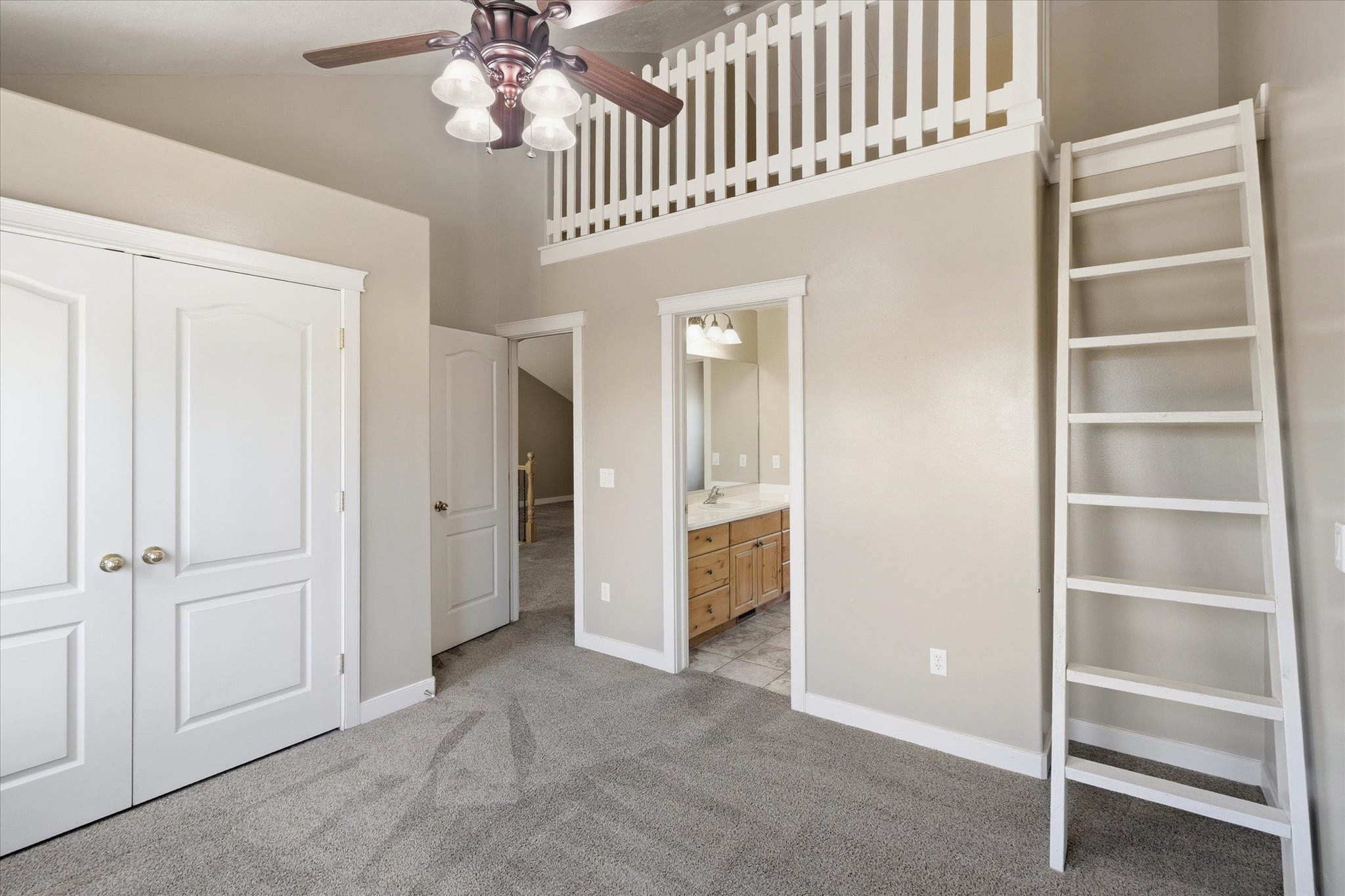 Carpeted room featuring a loft with white railing, a white wooden ladder, and a ceiling fan with light fixture