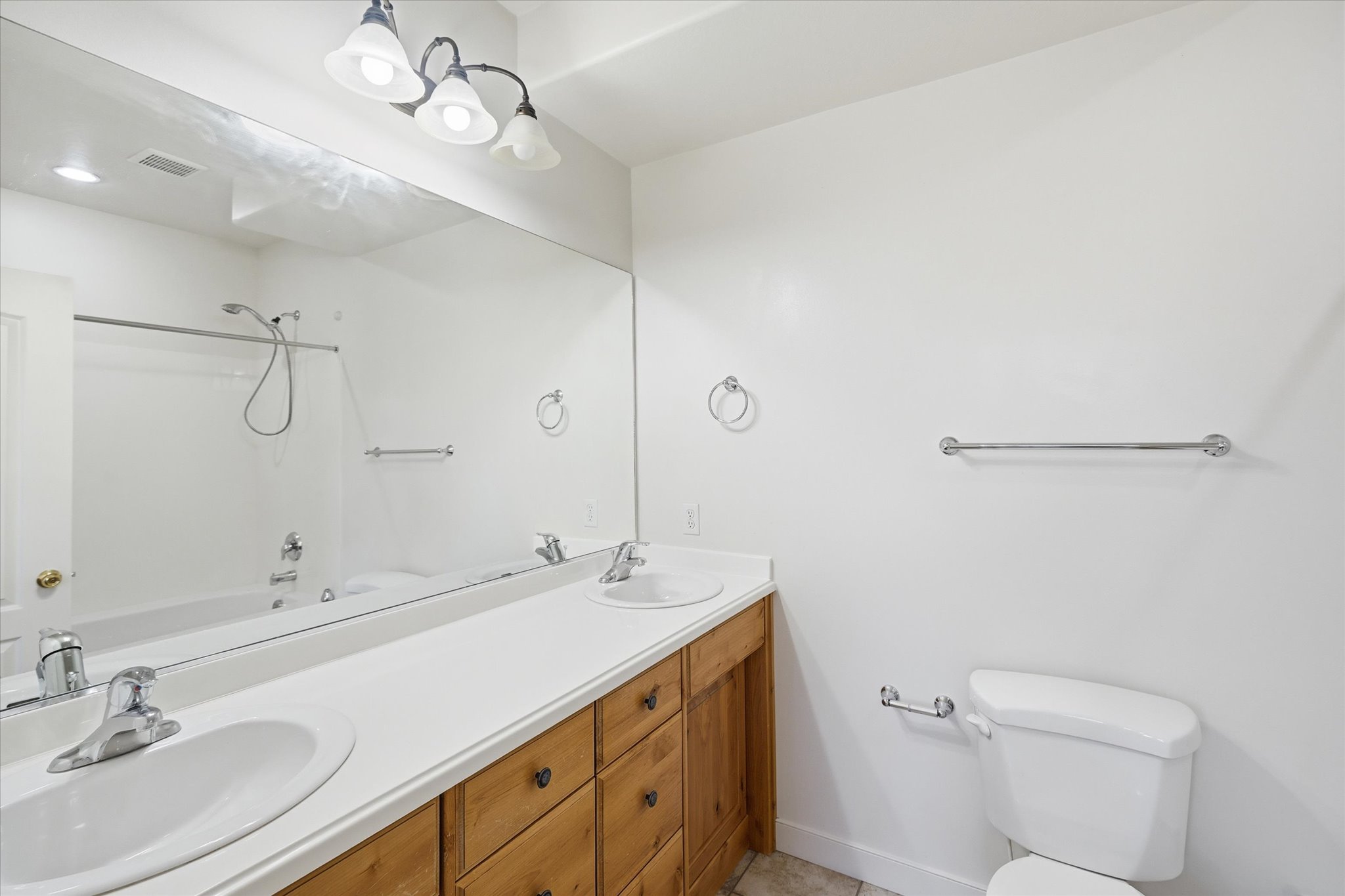 Dual vanity with integrated sinks, wood-finish cabinetry, and a full-width mirror