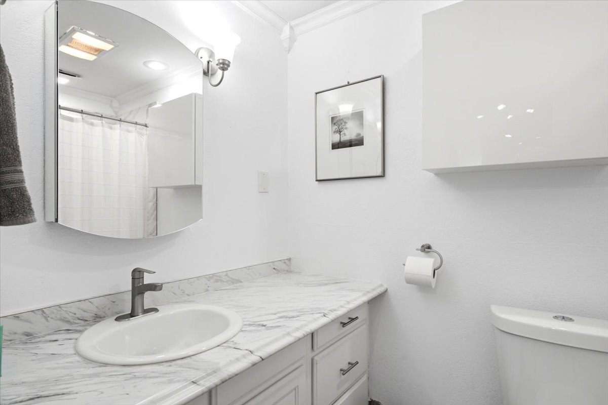 White vanity with a neutral-toned countertop featuring an undermount sink and brushed nickel faucet