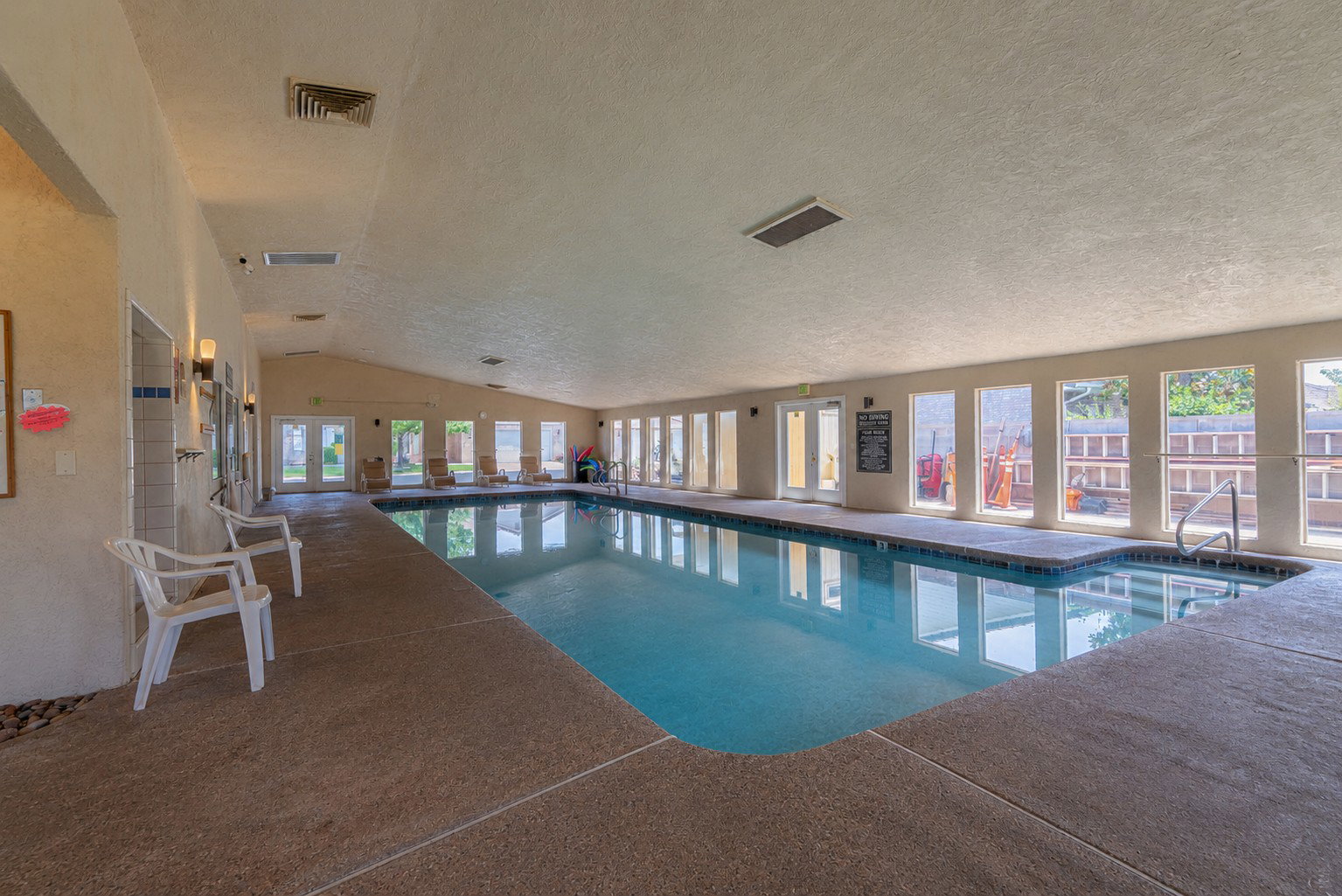 Indoor swimming pool featuring a large rectangular design with integrated steps and metal handrails