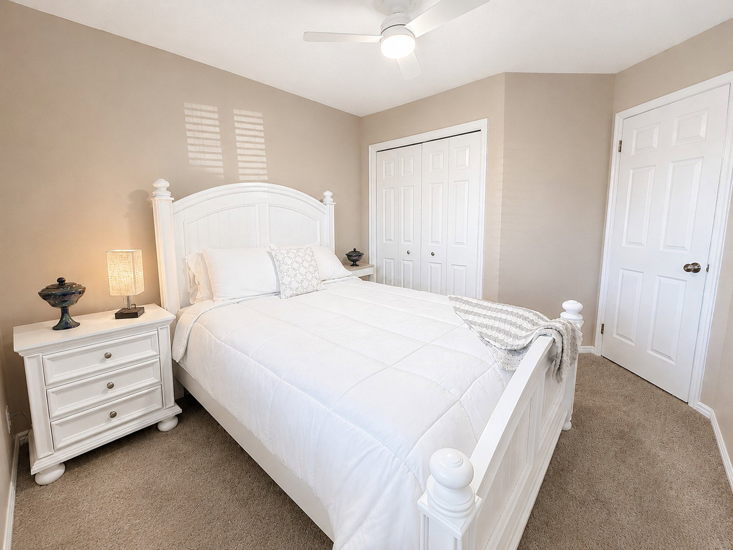 Carpeted bedroom with neutral wall tones and a white ceiling fan
