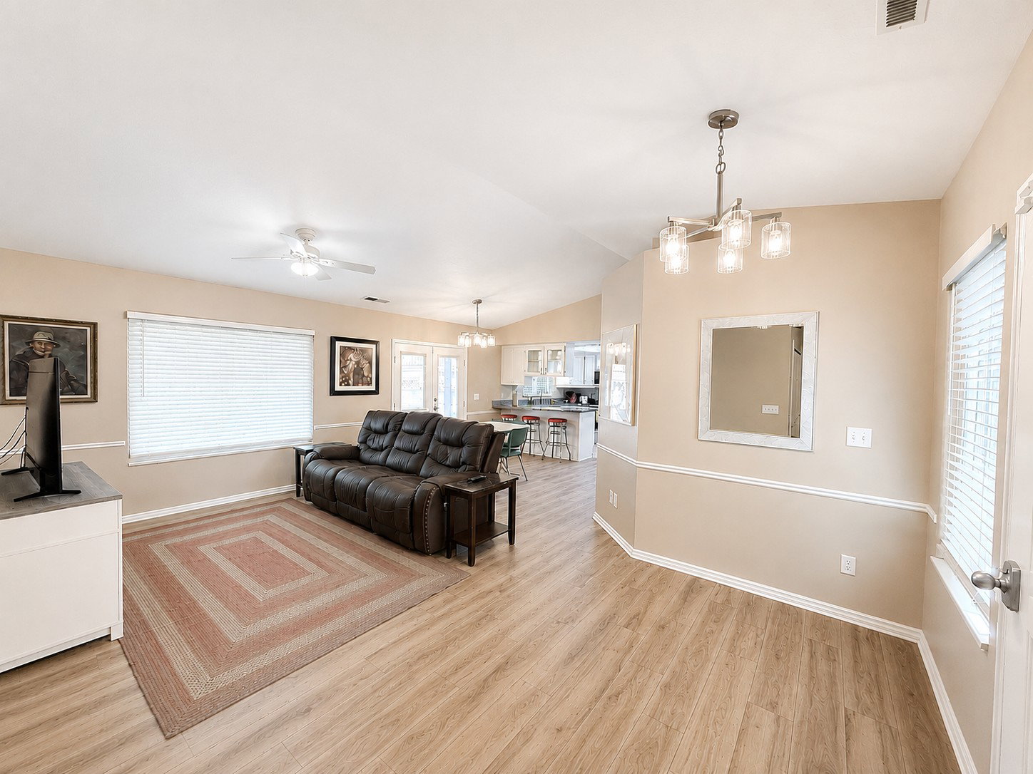 Spacious living area featuring wood-finish flooring, vaulted ceilings, and a contemporary chandelier