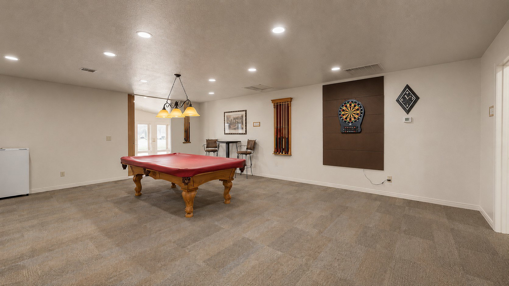 Spacious room featuring neutral carpeting, recessed lighting, and a chandelier-style light fixture