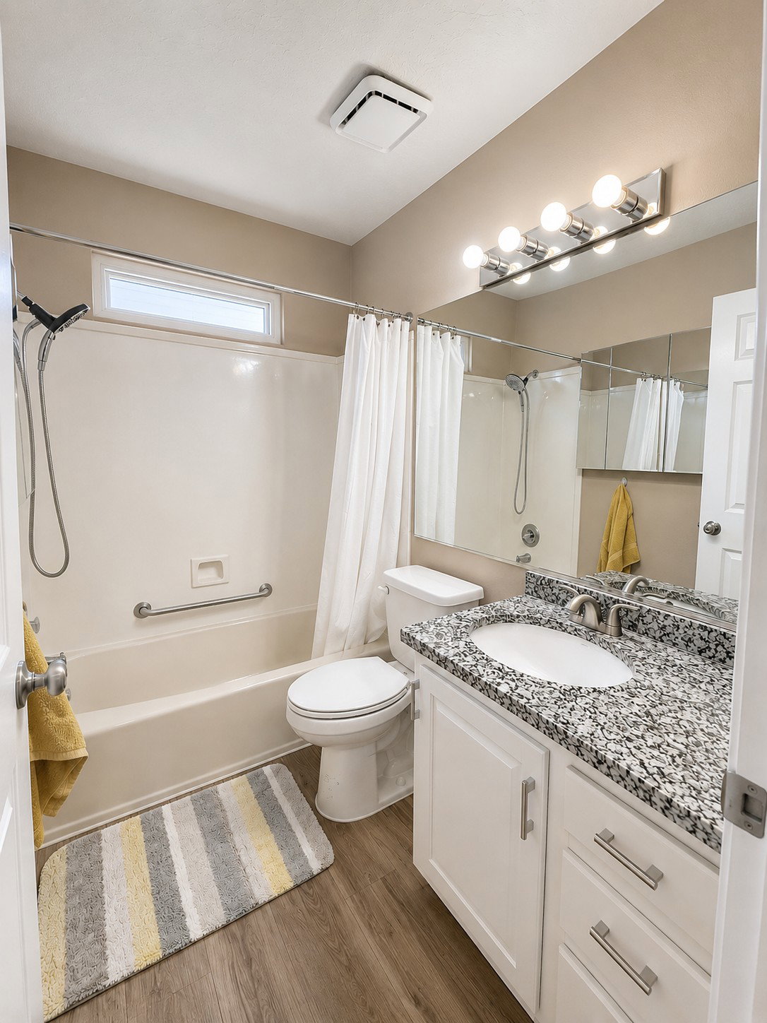 Bathroom featuring a white vanity with a speckled countertop, undermount sink, and brushed nickel fixtures