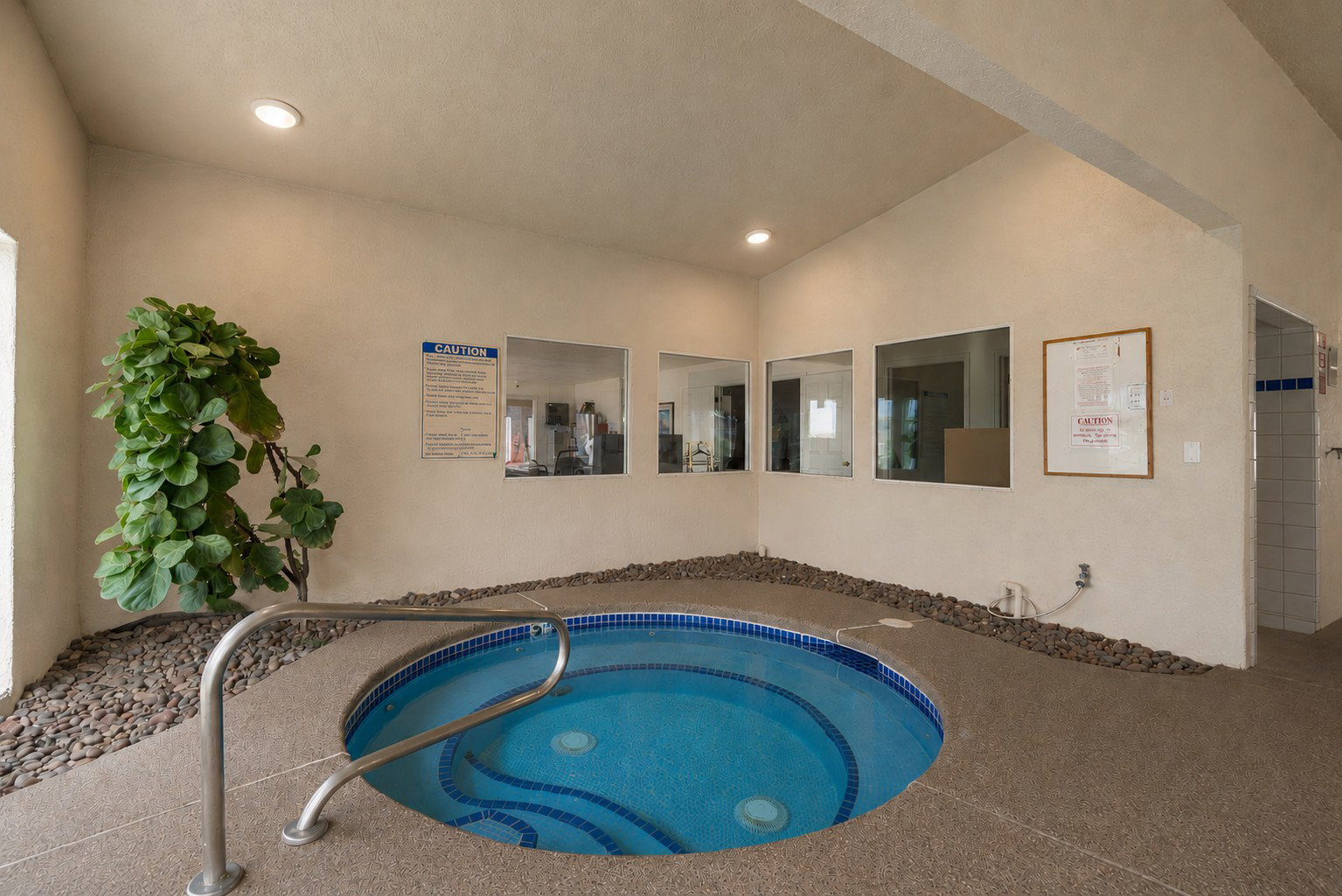 Indoor spa with a mosaic-tiled basin and stainless steel handrail