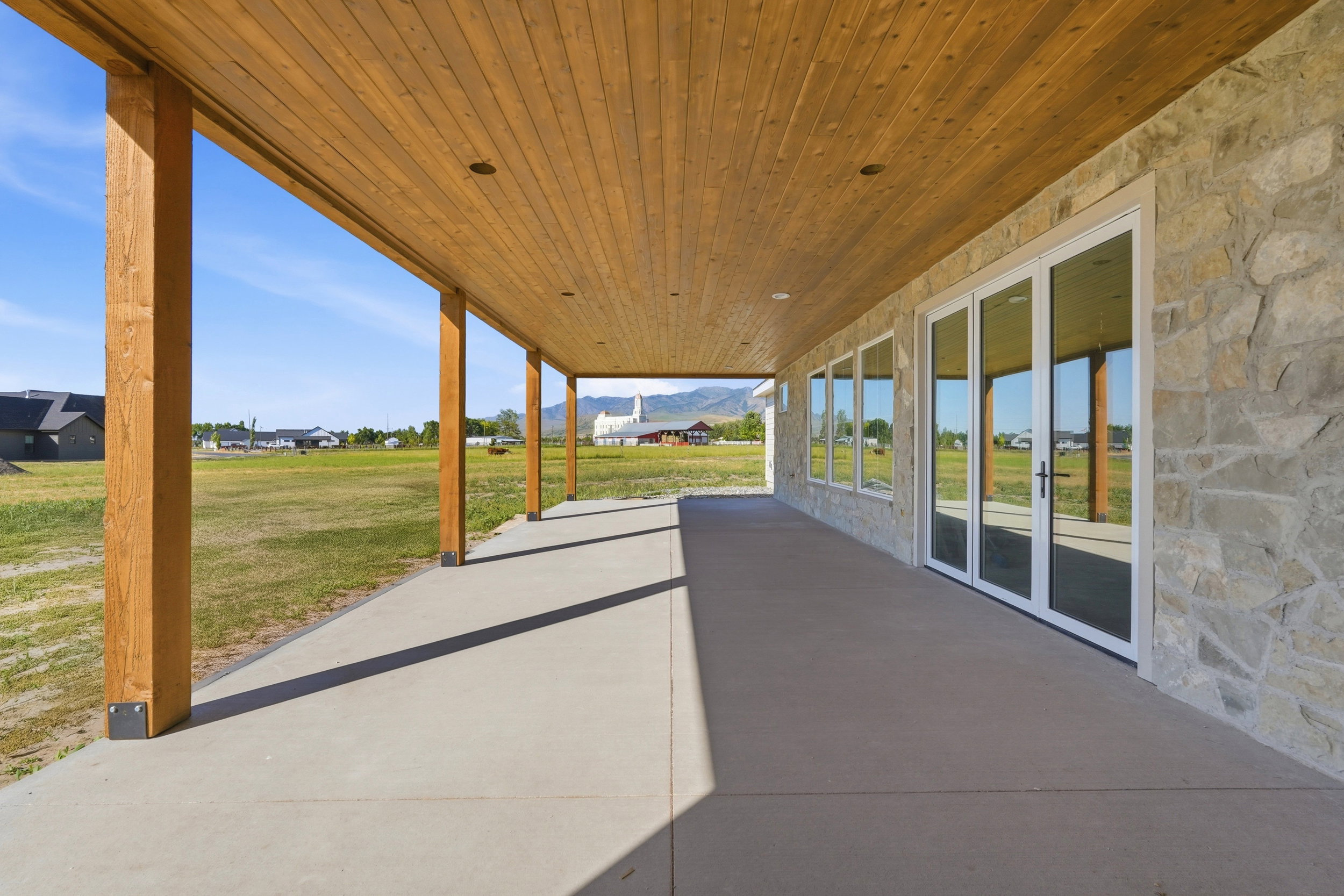 Expansive covered patio featuring a wood-plank ceiling, recessed lighting, and substantial wood support beams