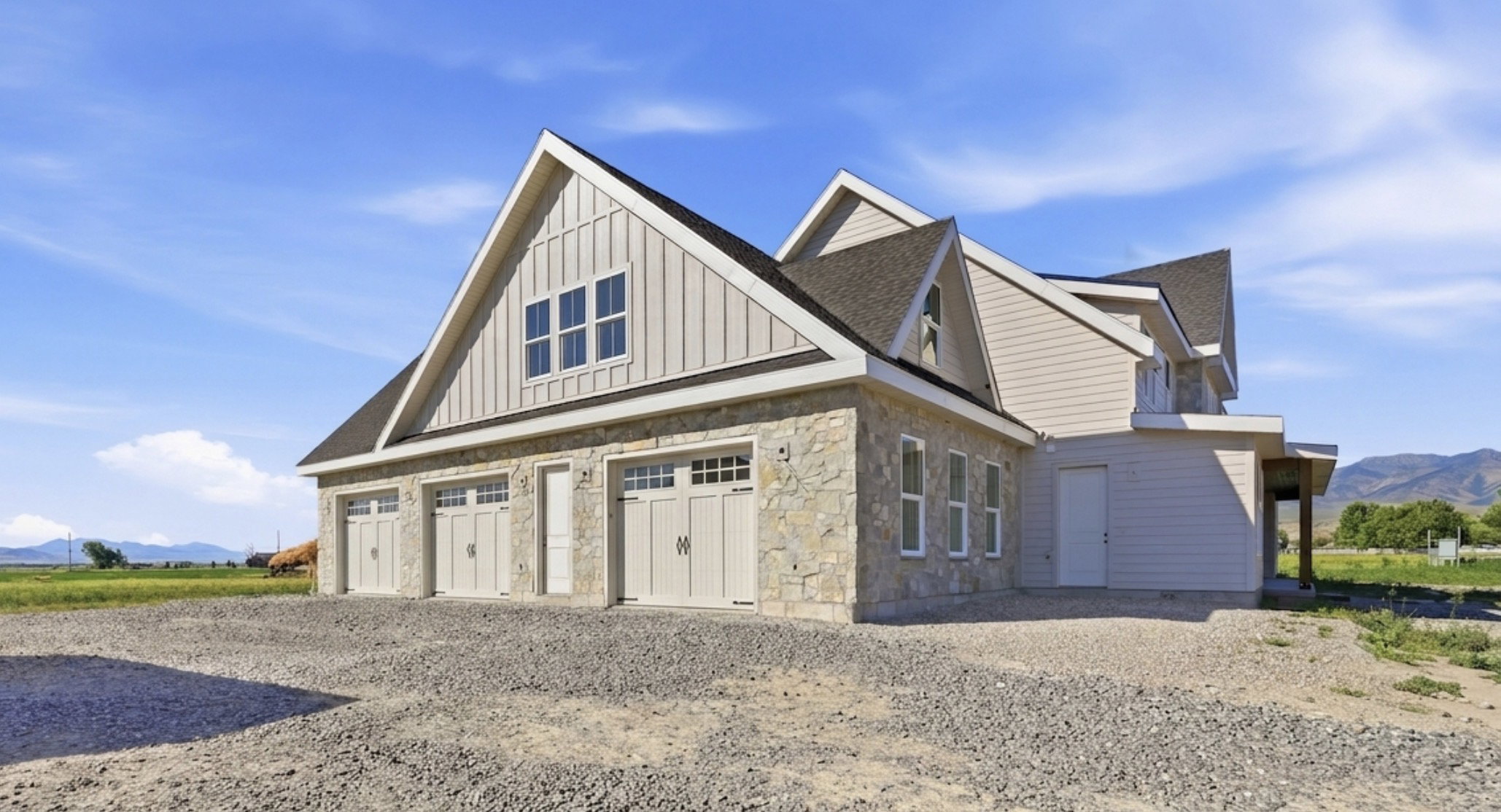 Stone and siding exterior featuring a three-car garage with carriage-style doors and upper window panels