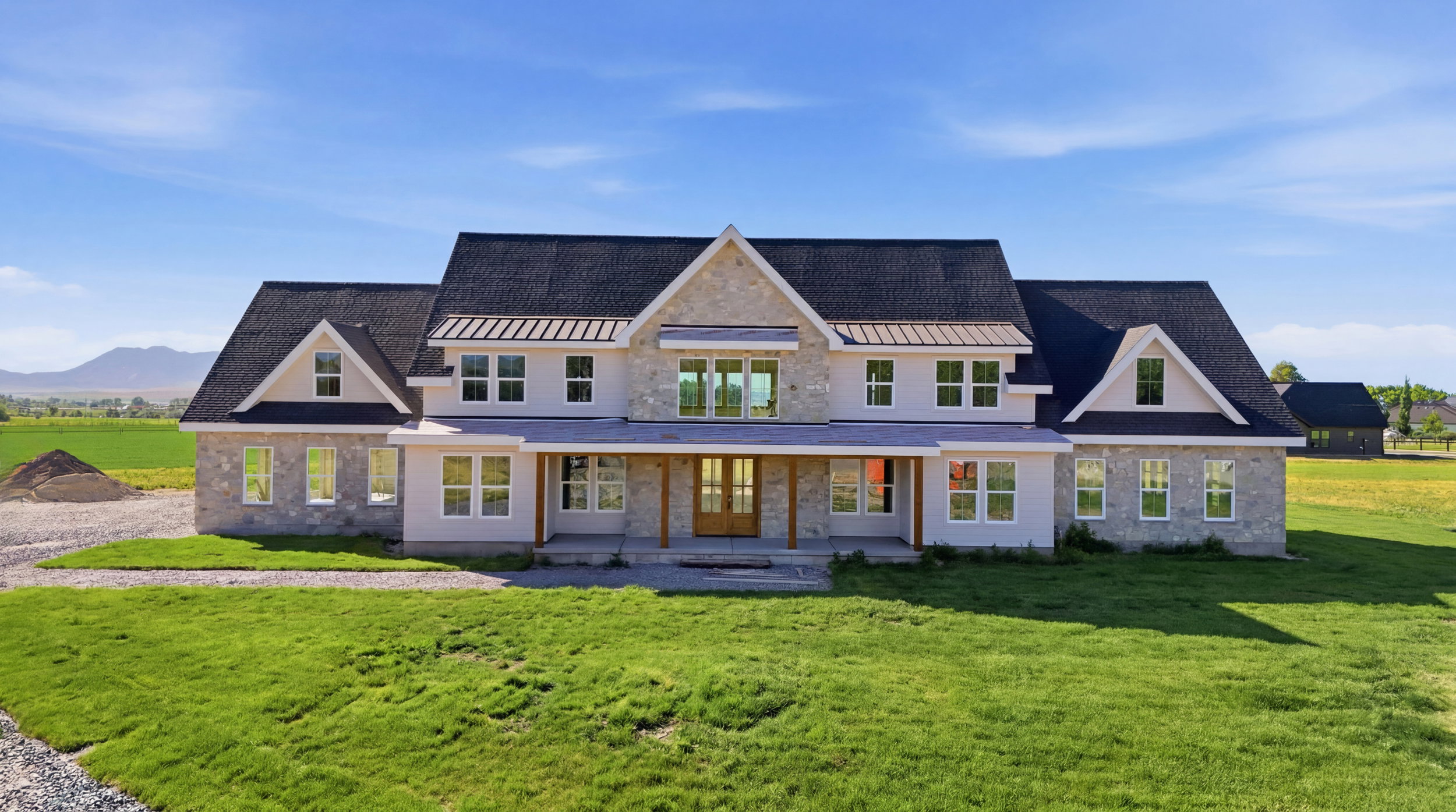 Modern farm-style residence featuring a prominent stone facade, dark shingle roof, and multiple gabled dormers