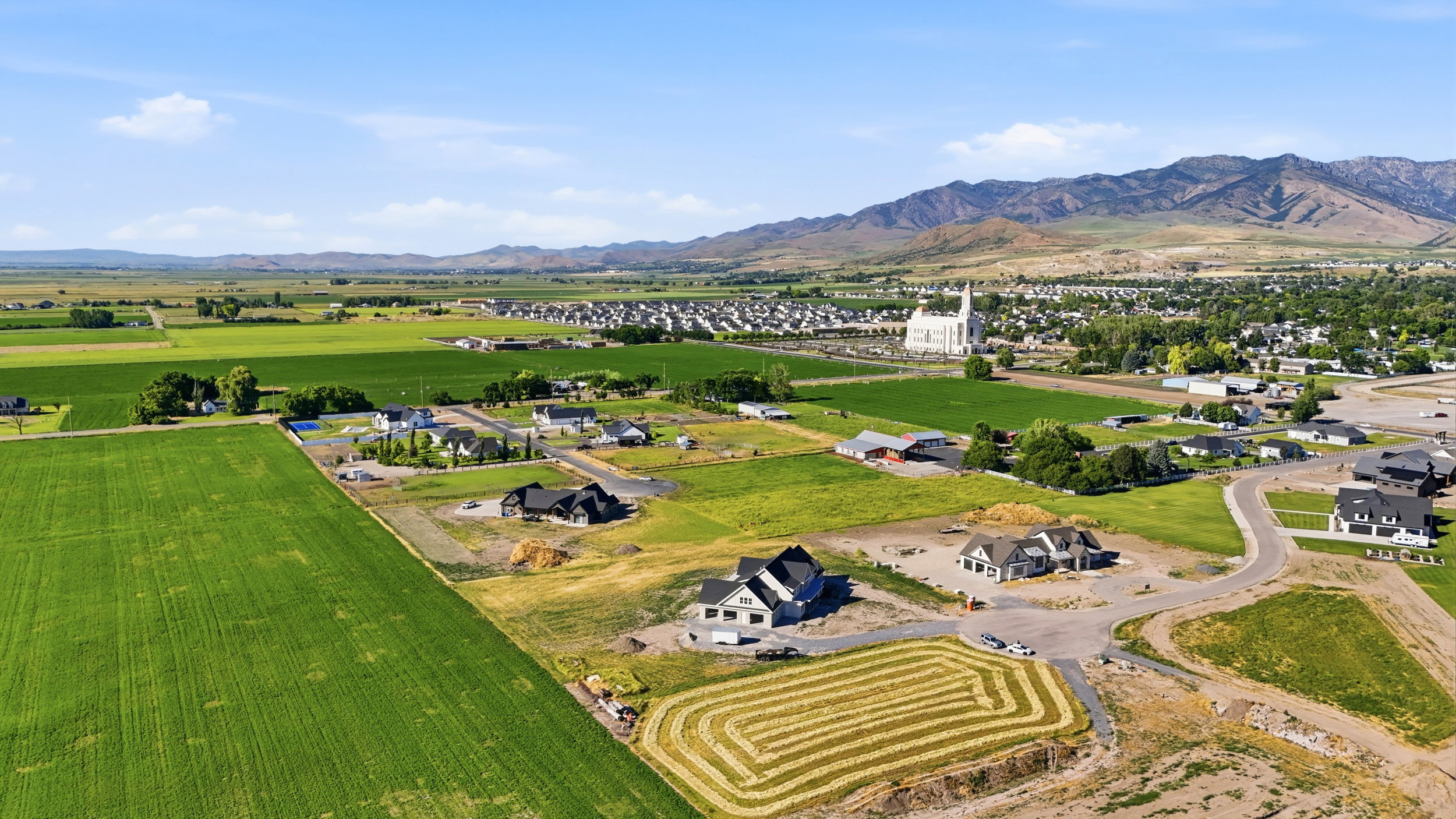 Expansive green fields, mountains, and residential development featuring various architectural styles