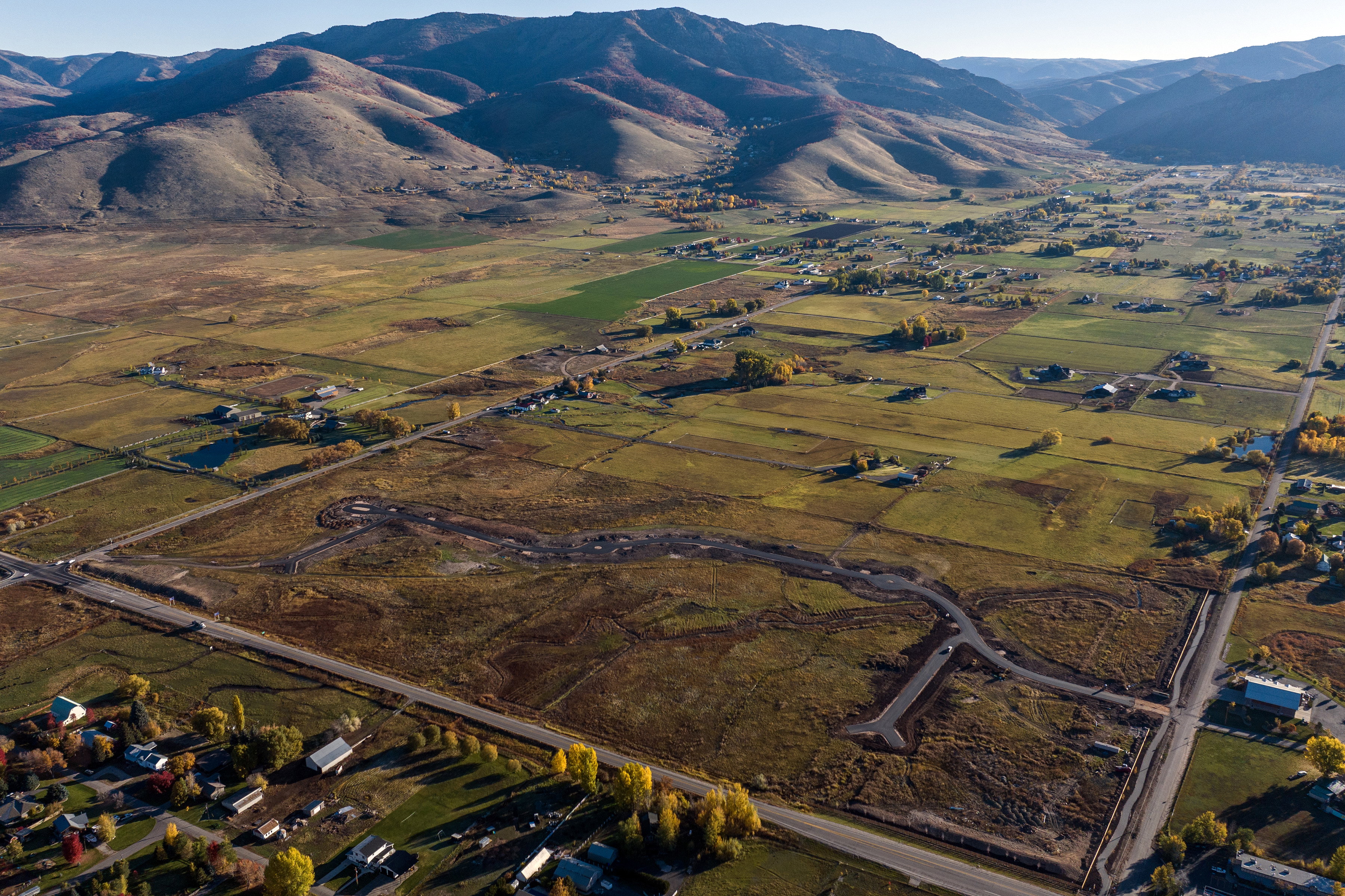 Expansive valley property featuring a partially developed road system, surrounding rural residences, and distant mountain topography