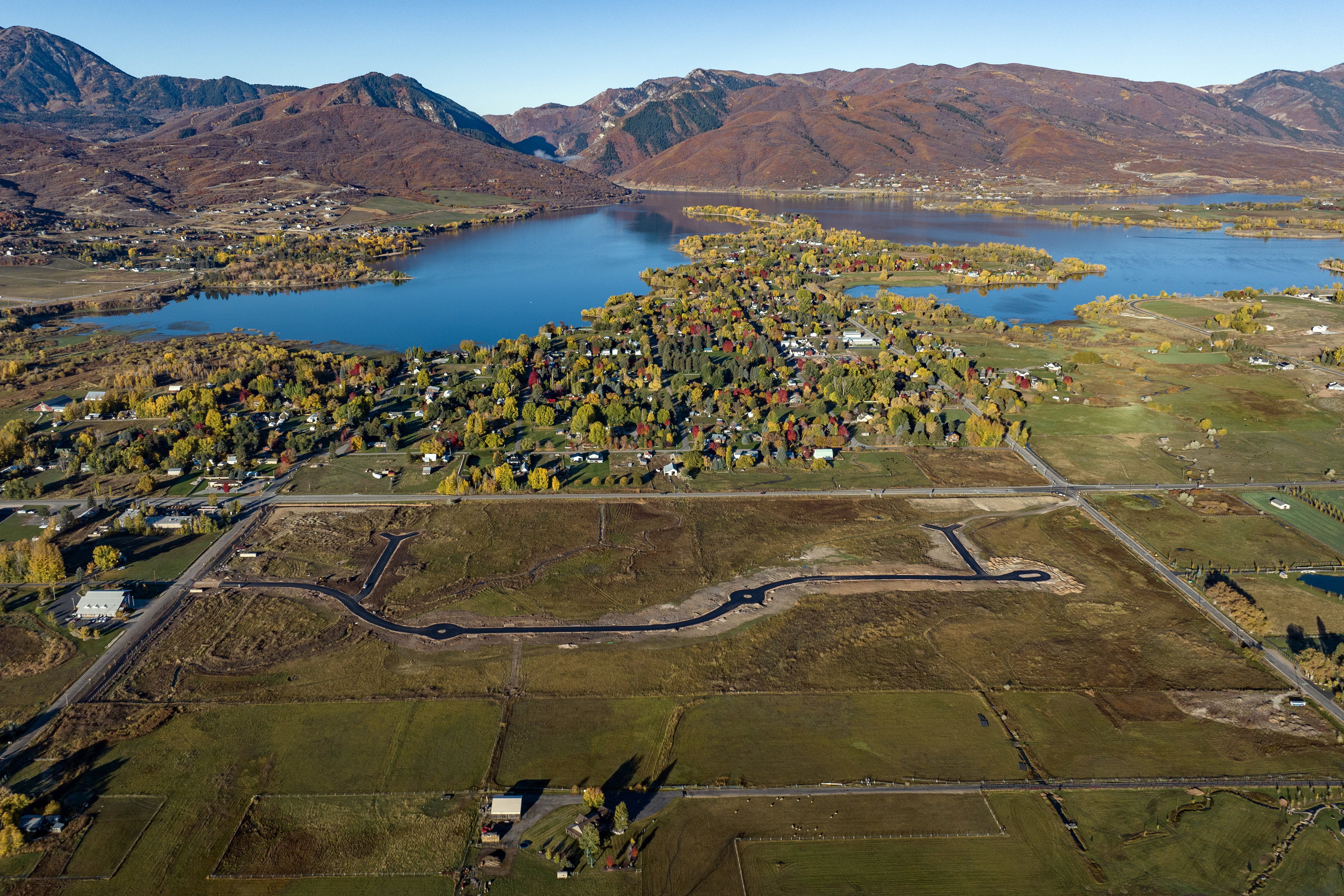 Aerial perspective showcasing a developing residential area with paved streets and cul-de-sacs, surrounded by open fields