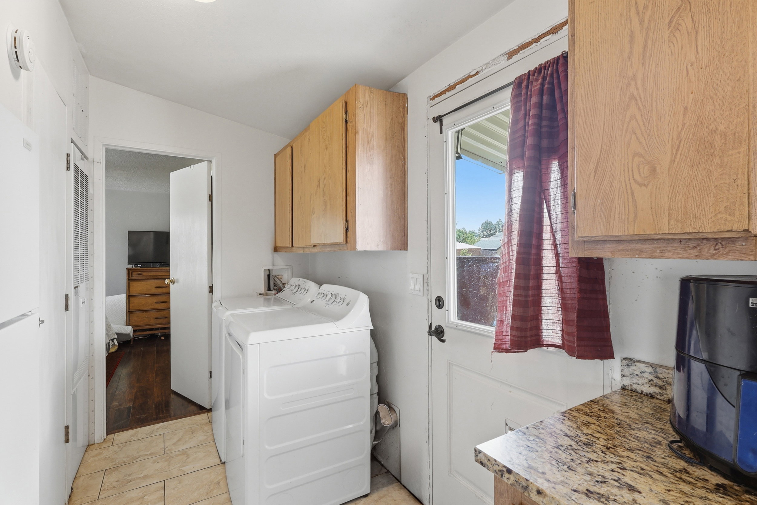 Laundry area featuring tile flooring, wood cabinetry, a granite-finish countertop, and an exterior door with a window