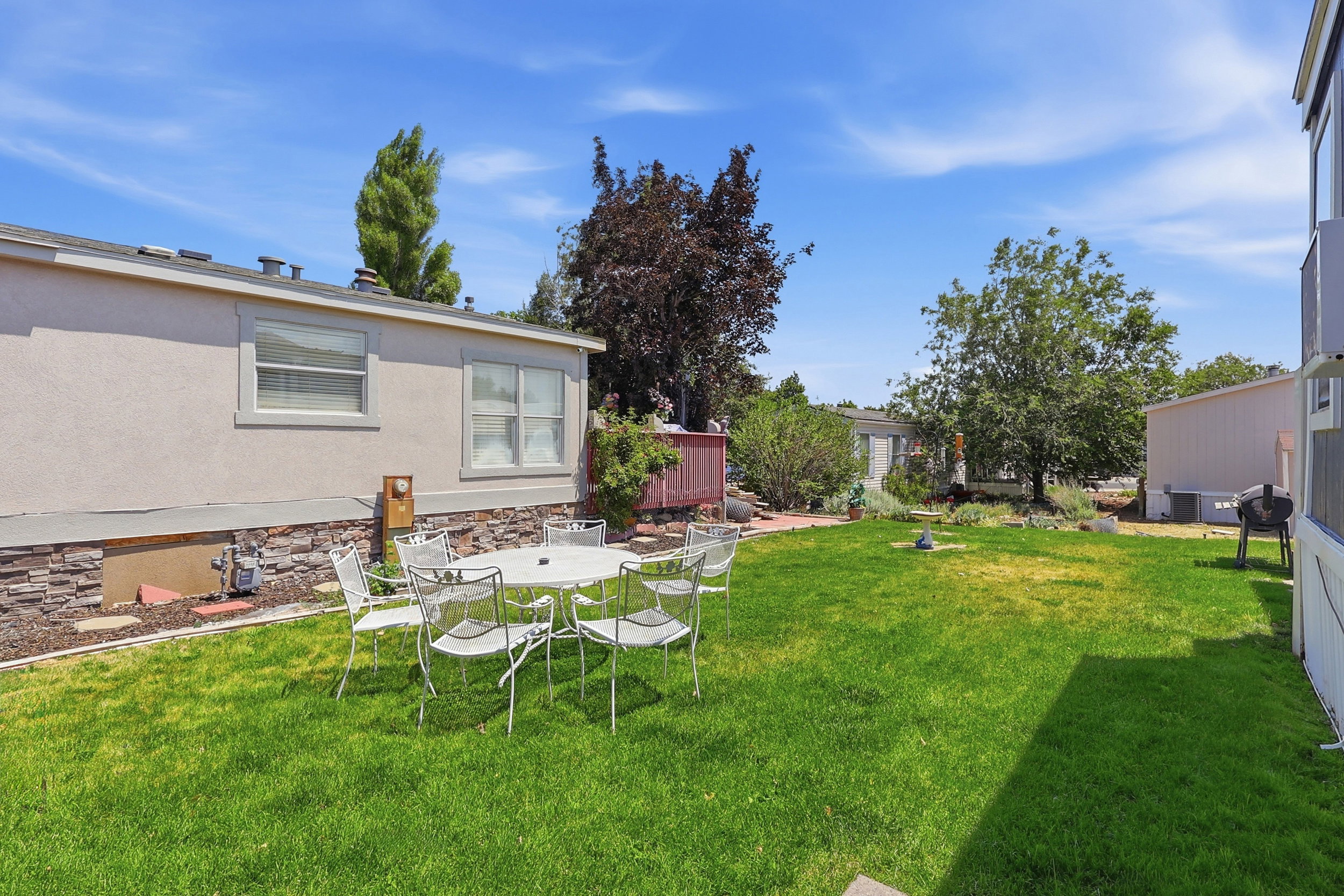 Expansive green lawn with mature trees and a stone-clad foundation