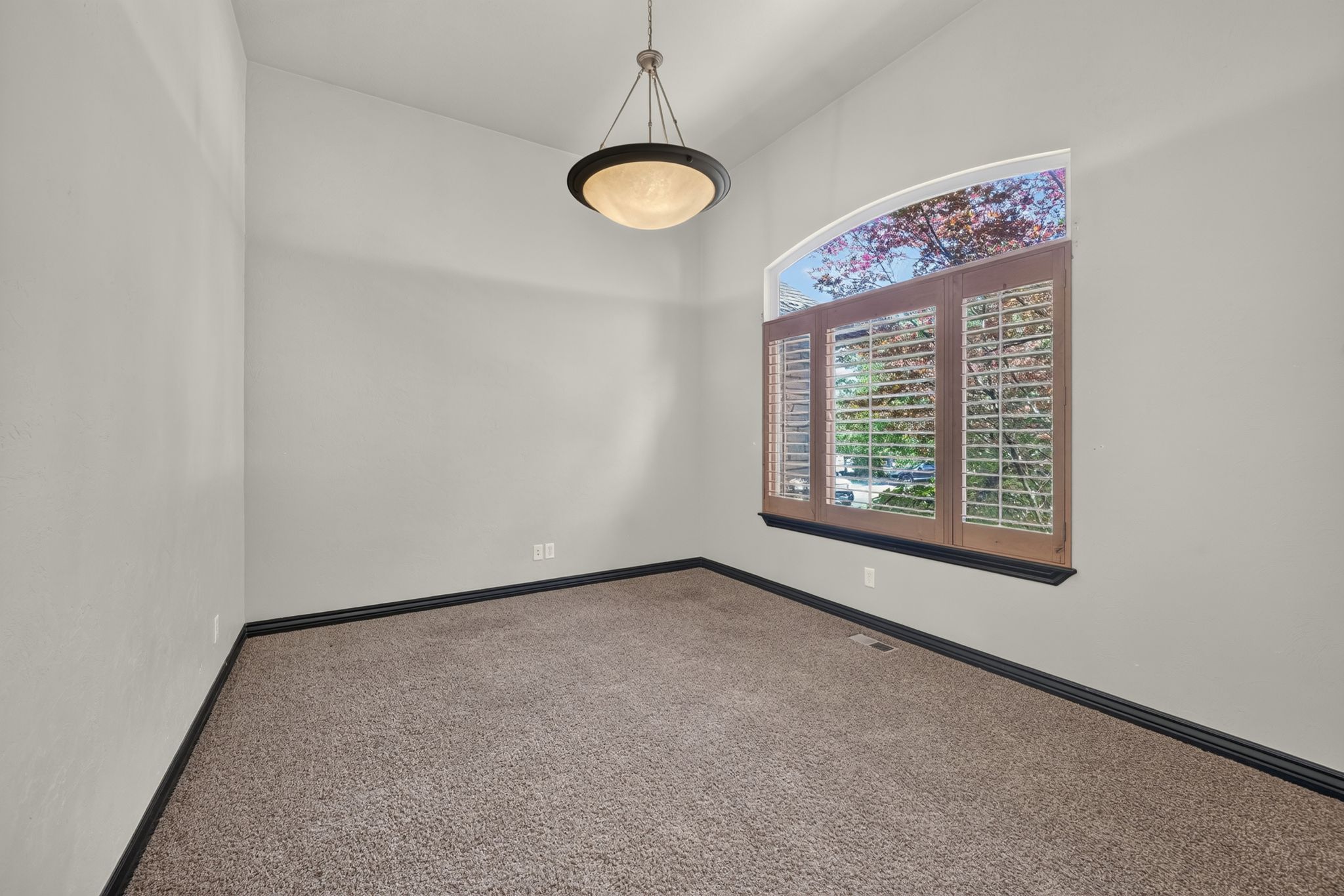 Interior room featuring a vaulted ceiling textured light-toned walls with plantation shutters