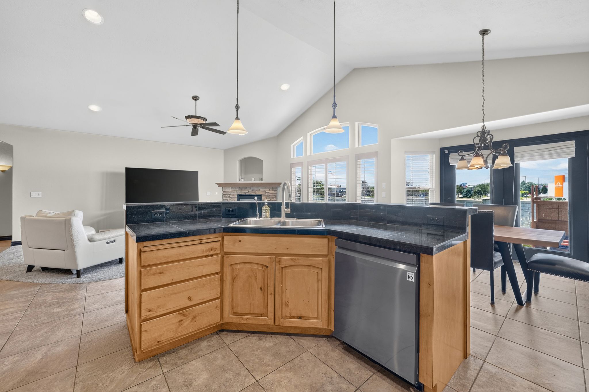 Kitchen island featuring a double-basin sink, stainless steel dishwasher, and natural wood cabinetry