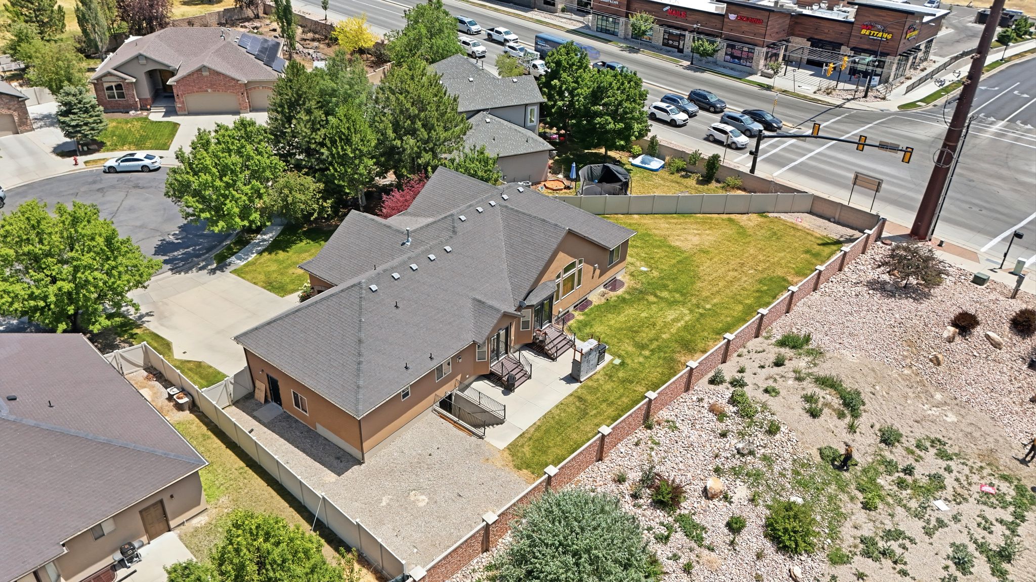 Property featuring a spacious backyard with a concrete patio, mature trees, and a brick-capped privacy fence