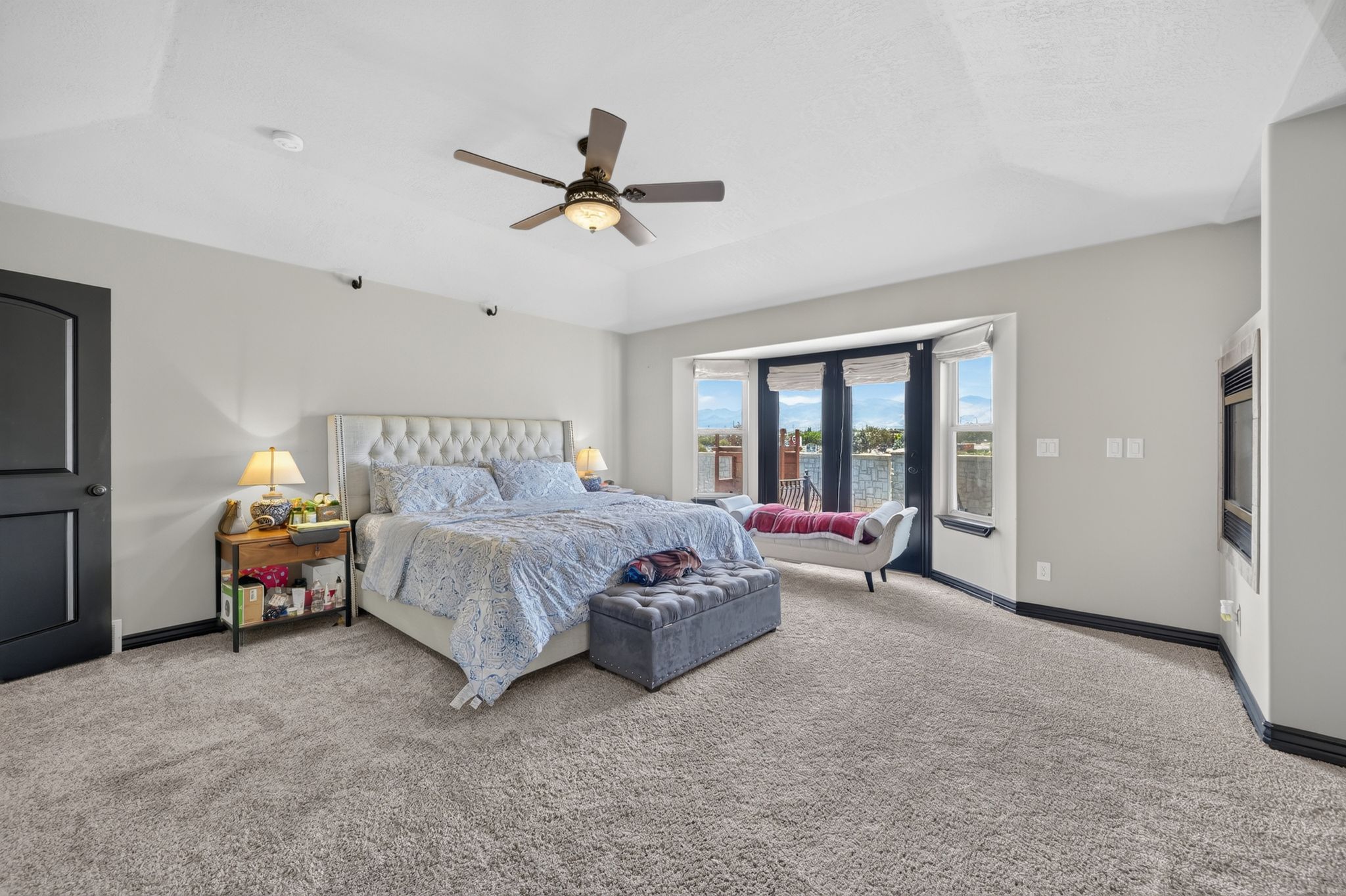 Spacious Primary room featuring light-colored carpeting, a multi-pane bay window, and a ceiling fan with integrated lighting