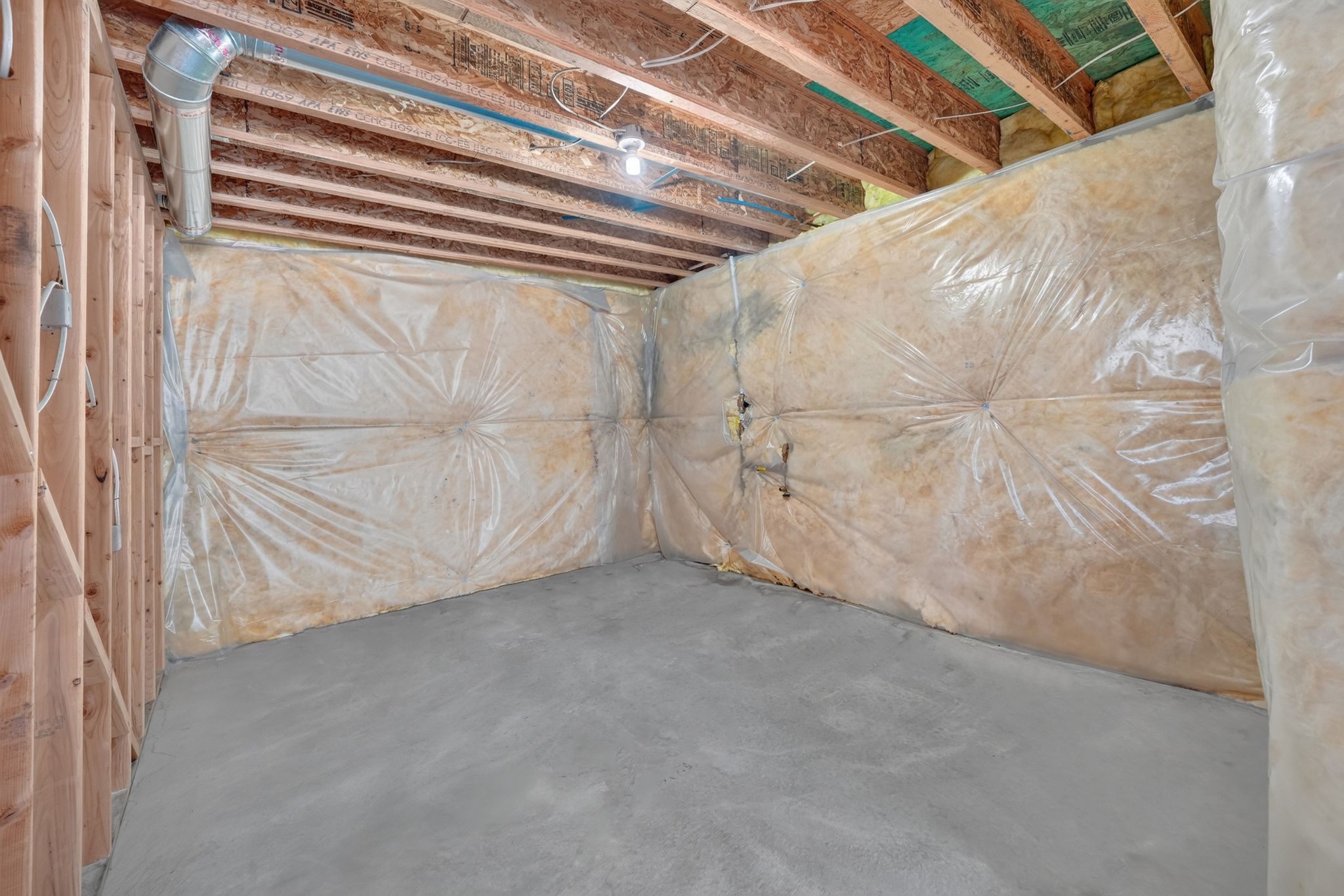Unfinished basement with concrete flooring, exposed wood framing, and ceiling joists