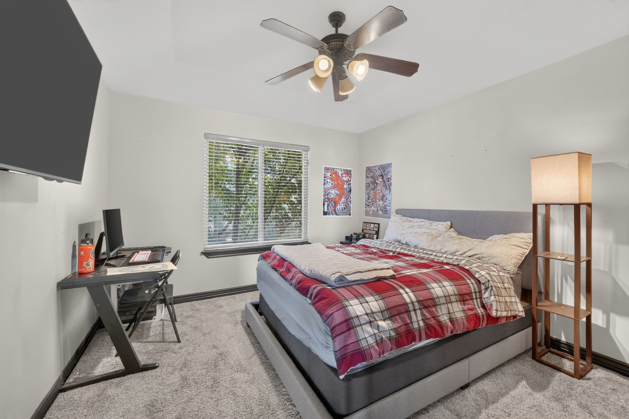 Carpeted Second bedroom featuring a ceiling fan with integrated lighting, a window with blinds, and a built-in wall-mounted television