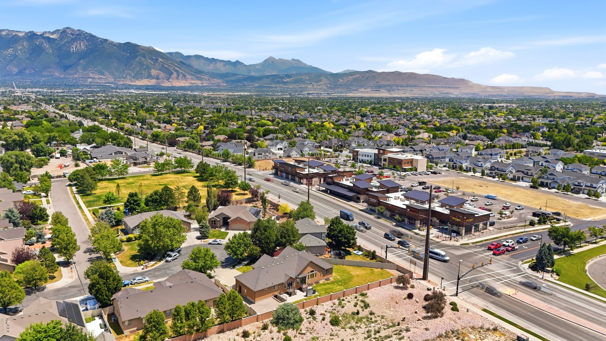 Expansive aerial perspective showcasing a residential community with mature trees and mountain scenery