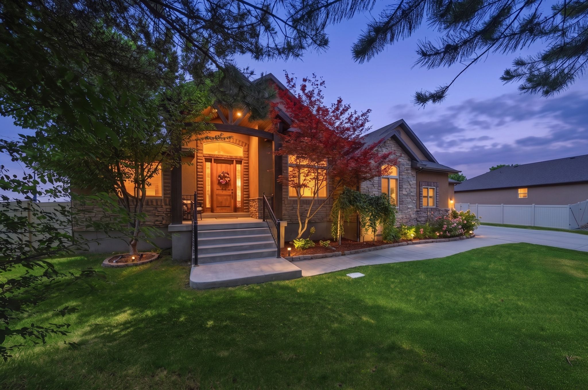 Stone and stucco exterior featuring a covered entry, concrete steps with metal railings, and a wood-finish front door