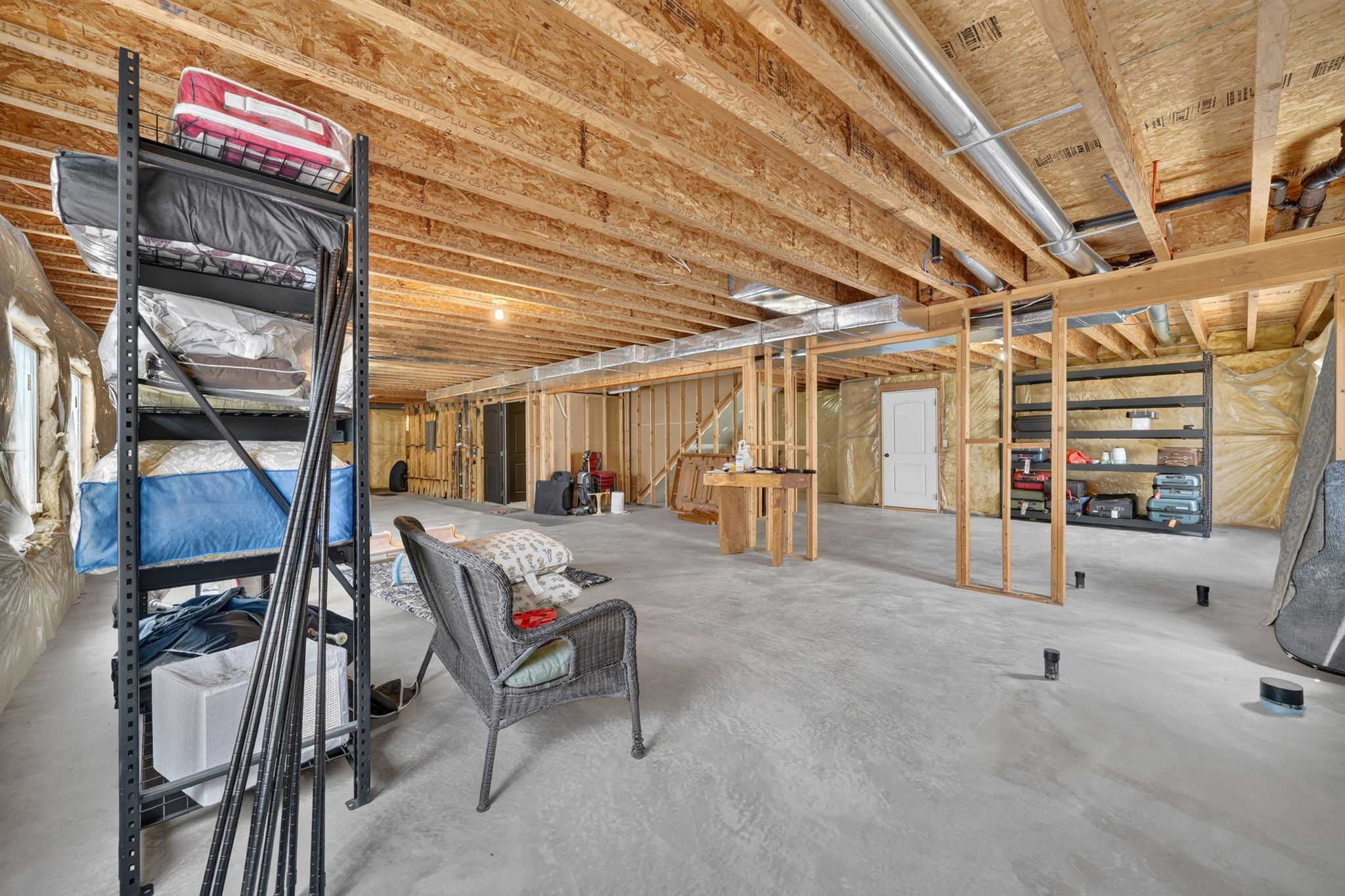 Unfinished basement with exposed wood joists and concrete flooring