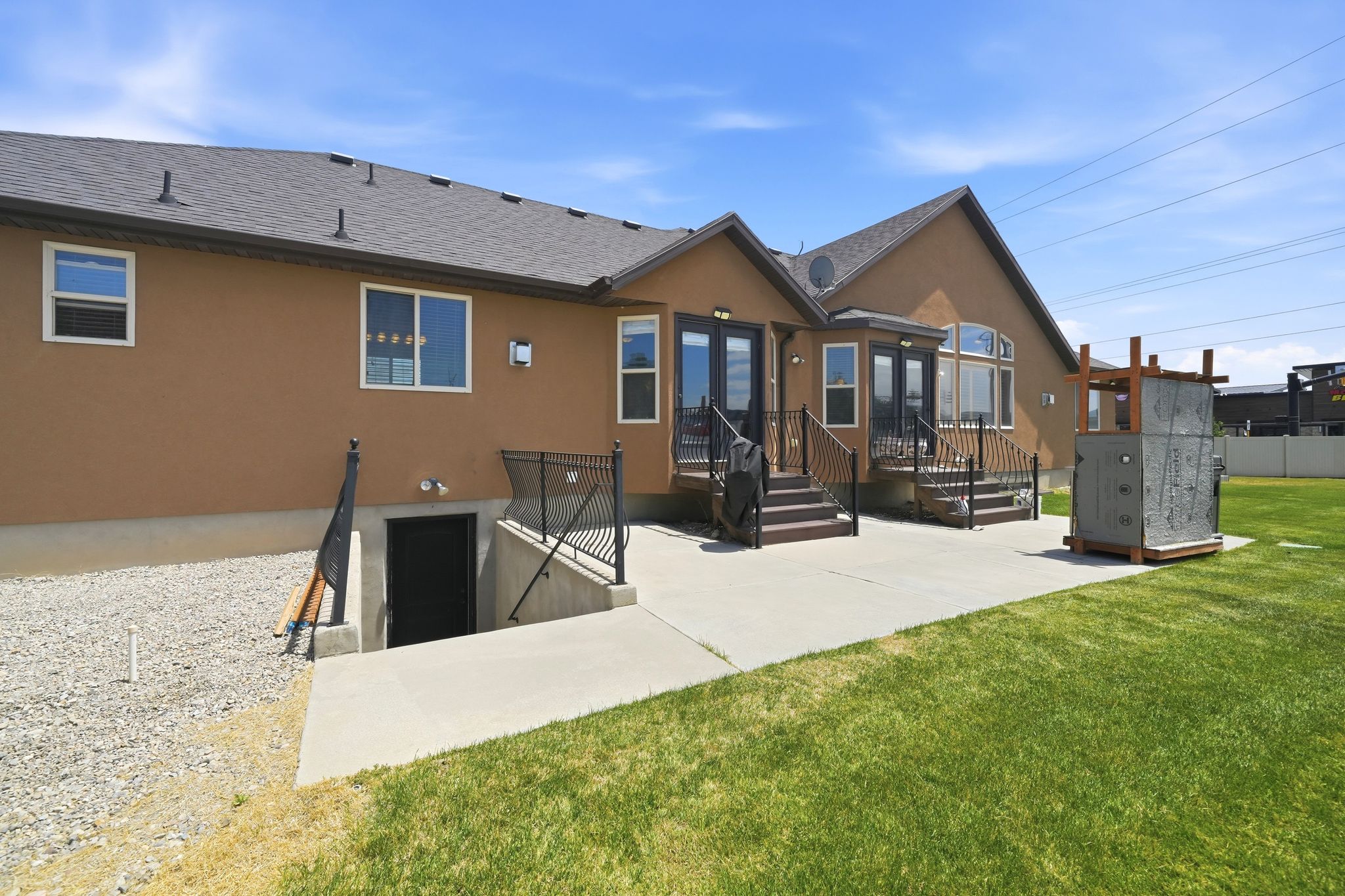 Expansive backyard featuring a manicured lawn, concrete patio, and a dedicated basement entrance