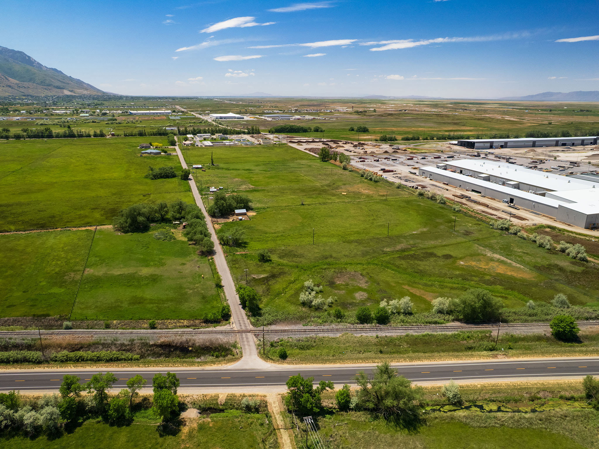 Expansive green acreage with a paved roadway and rail line traversing the property