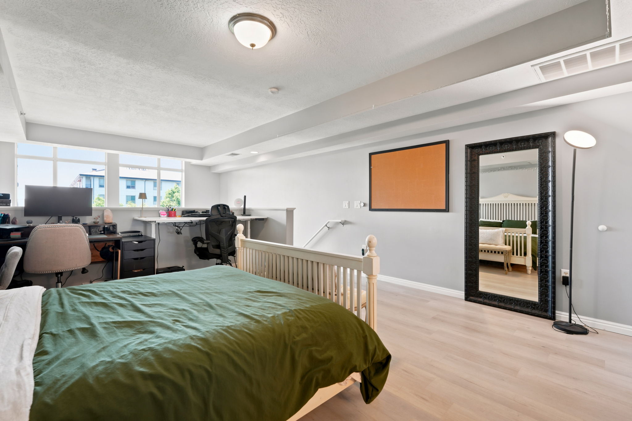 Room featuring light wood-finish flooring, a broad horizontal window, and a built-in recessed desk area