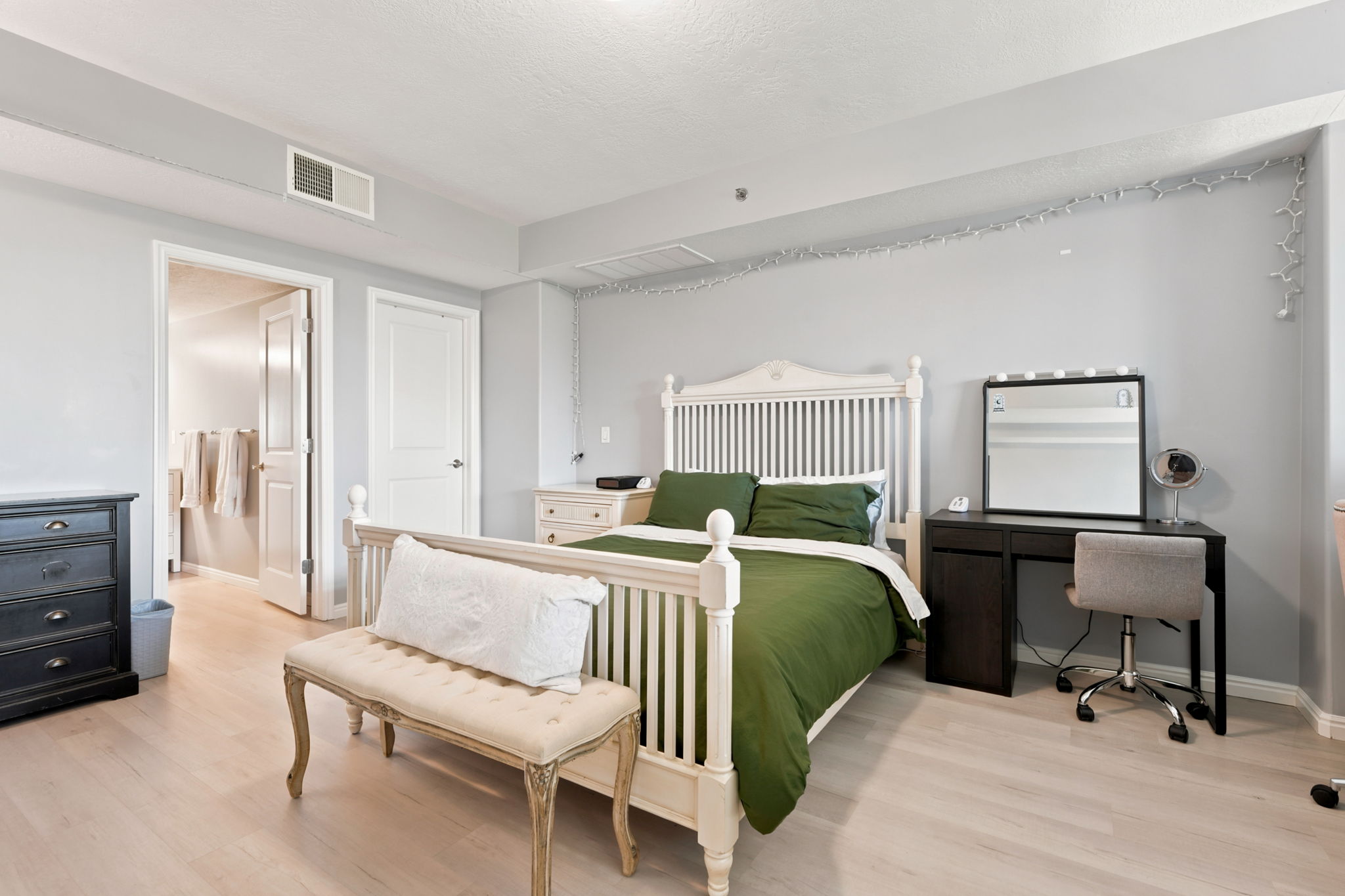 Bedroom featuring light wood-finish flooring, light gray walls, white trim, and a white interior door