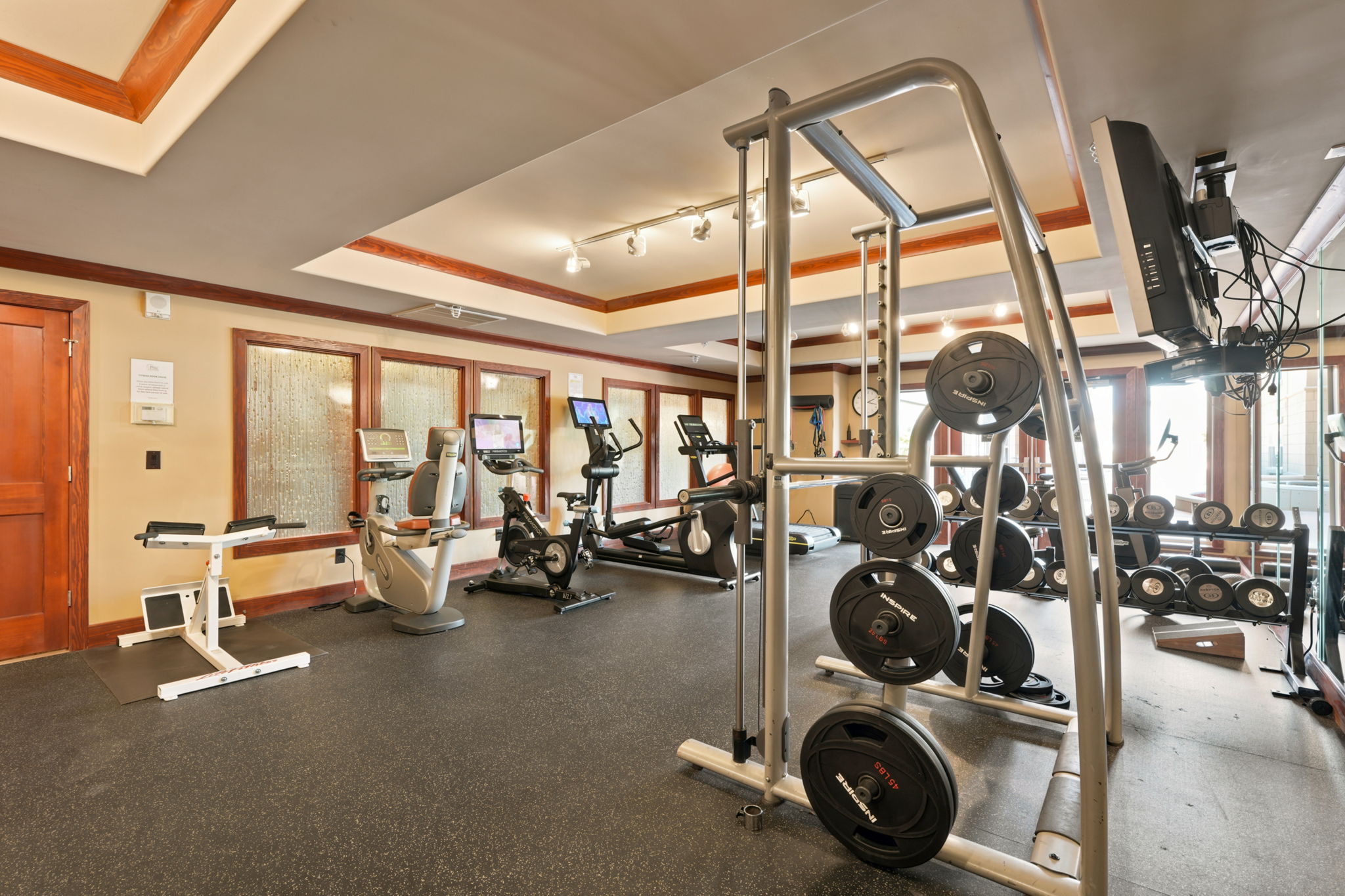 Dedicated fitness room featuring rubberized flooring, recessed lighting, wood trim, and a multi-pane window design