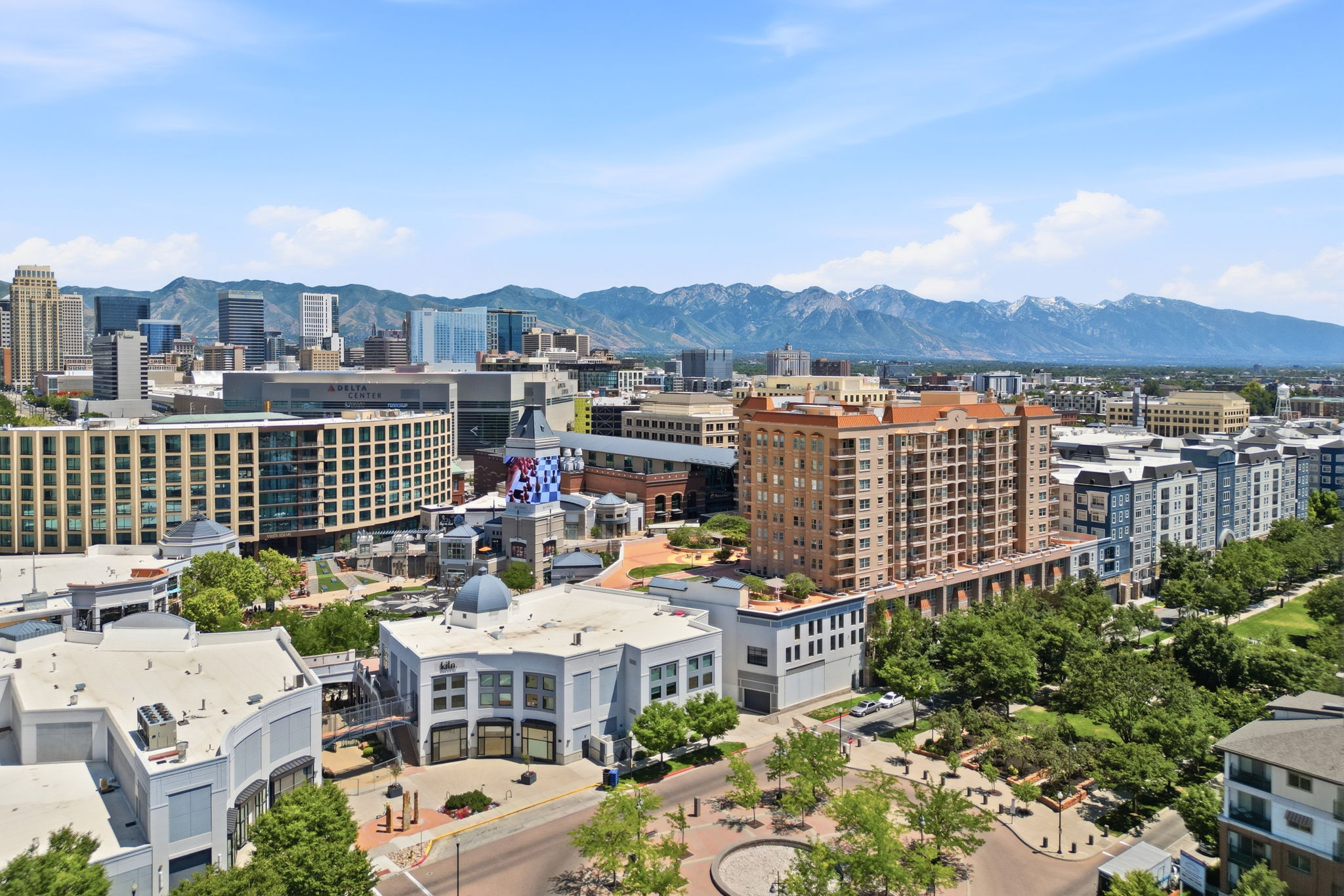 Expansive cityscape with a mountain backdrop, featuring a mix of modern and traditional architecture, tree-lined streets, and multiple building types