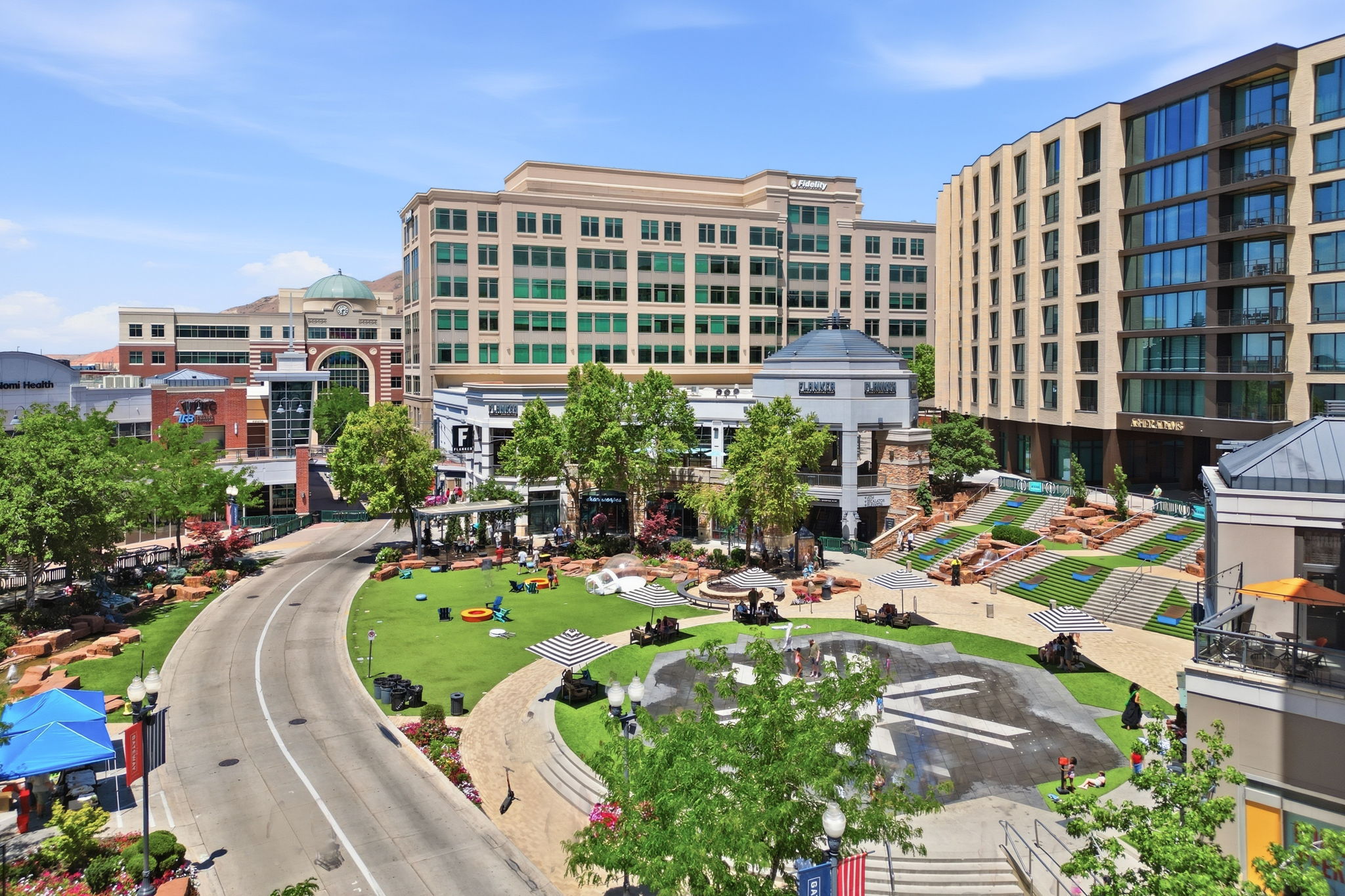Urban landscape featuring a central green space, surrounded by multi-story commercial and residential buildings