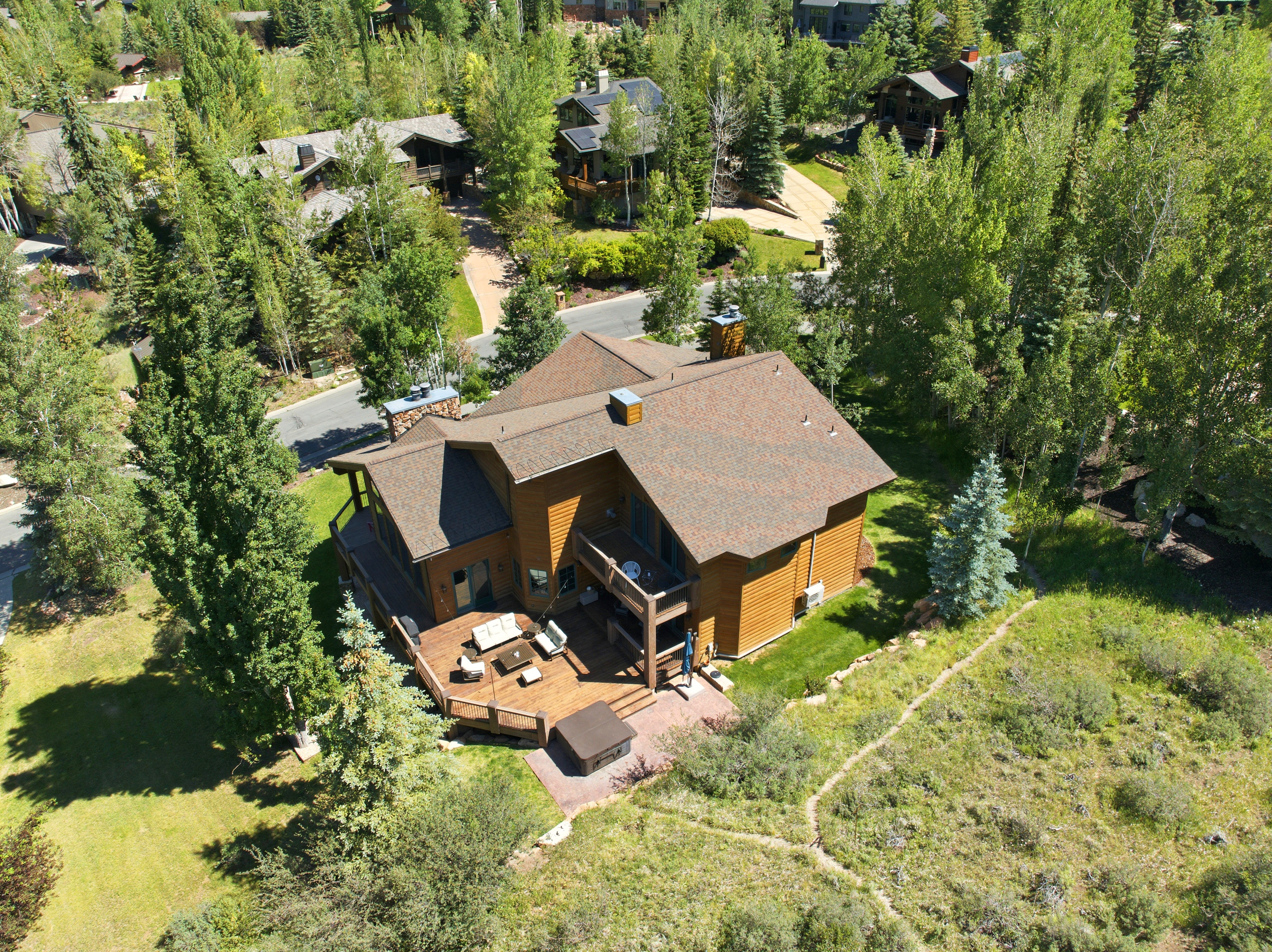 Wood-sided residence featuring a multi-level deck, a shingle roof, and multiple chimneys
