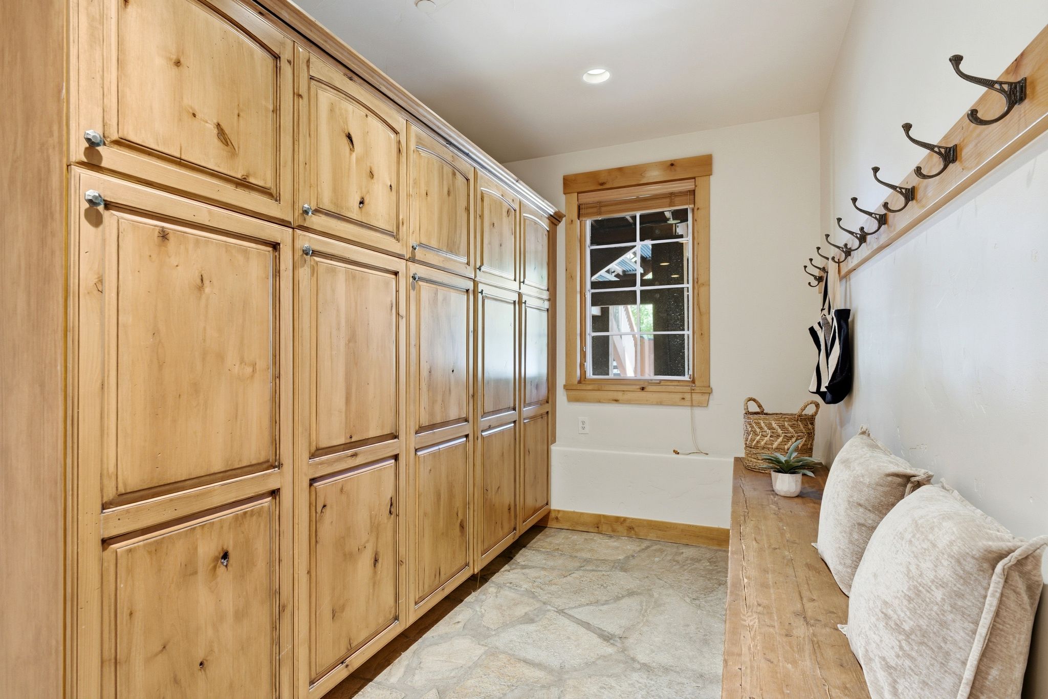 Built-in wood cabinetry providing extensive storage, complemented by a distressed wood bench and coordinating wood trim around the window and along the wall