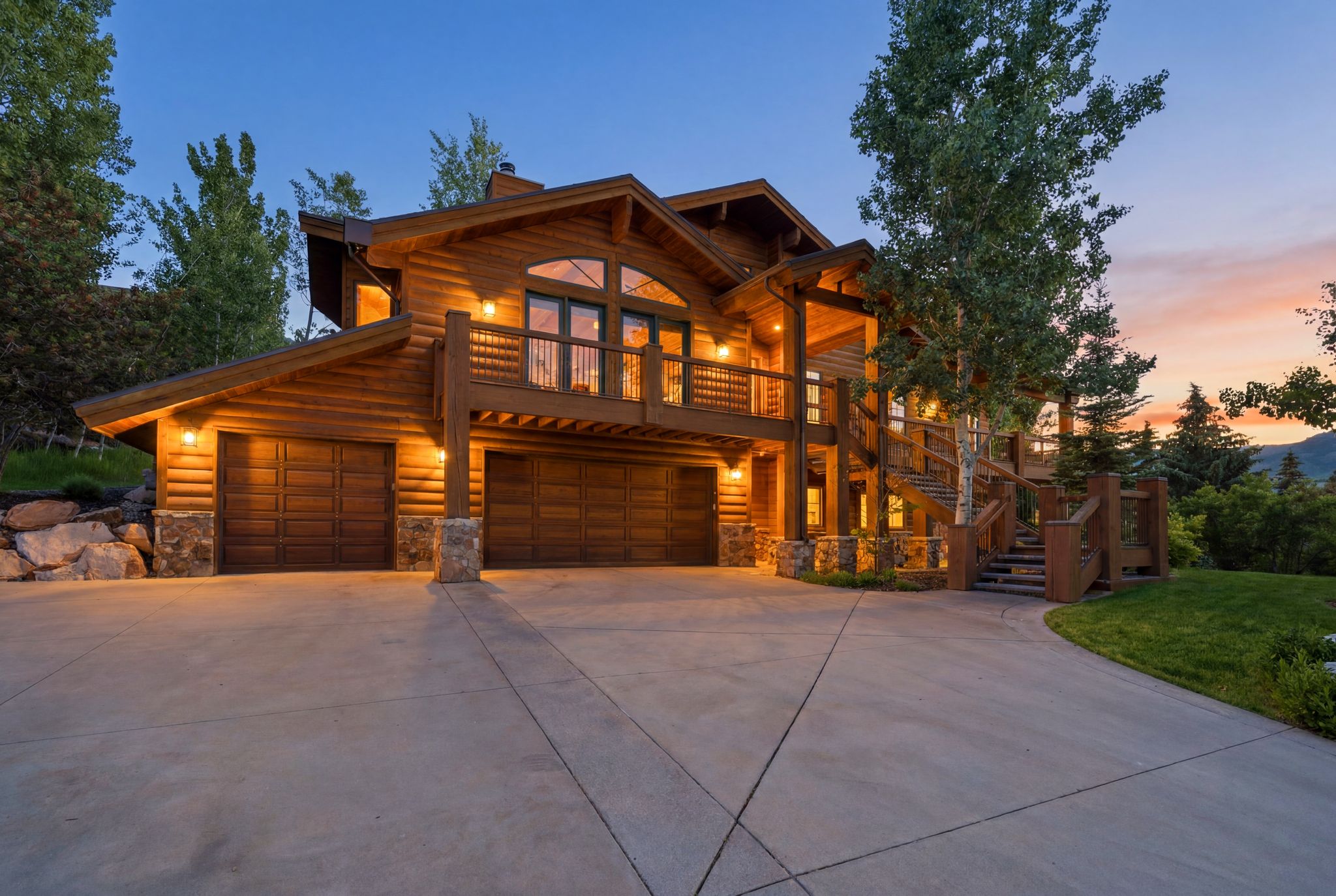 Rustic log home featuring a multi-level design, a prominent balcony, and a multi-car garage with wood-paneled doors