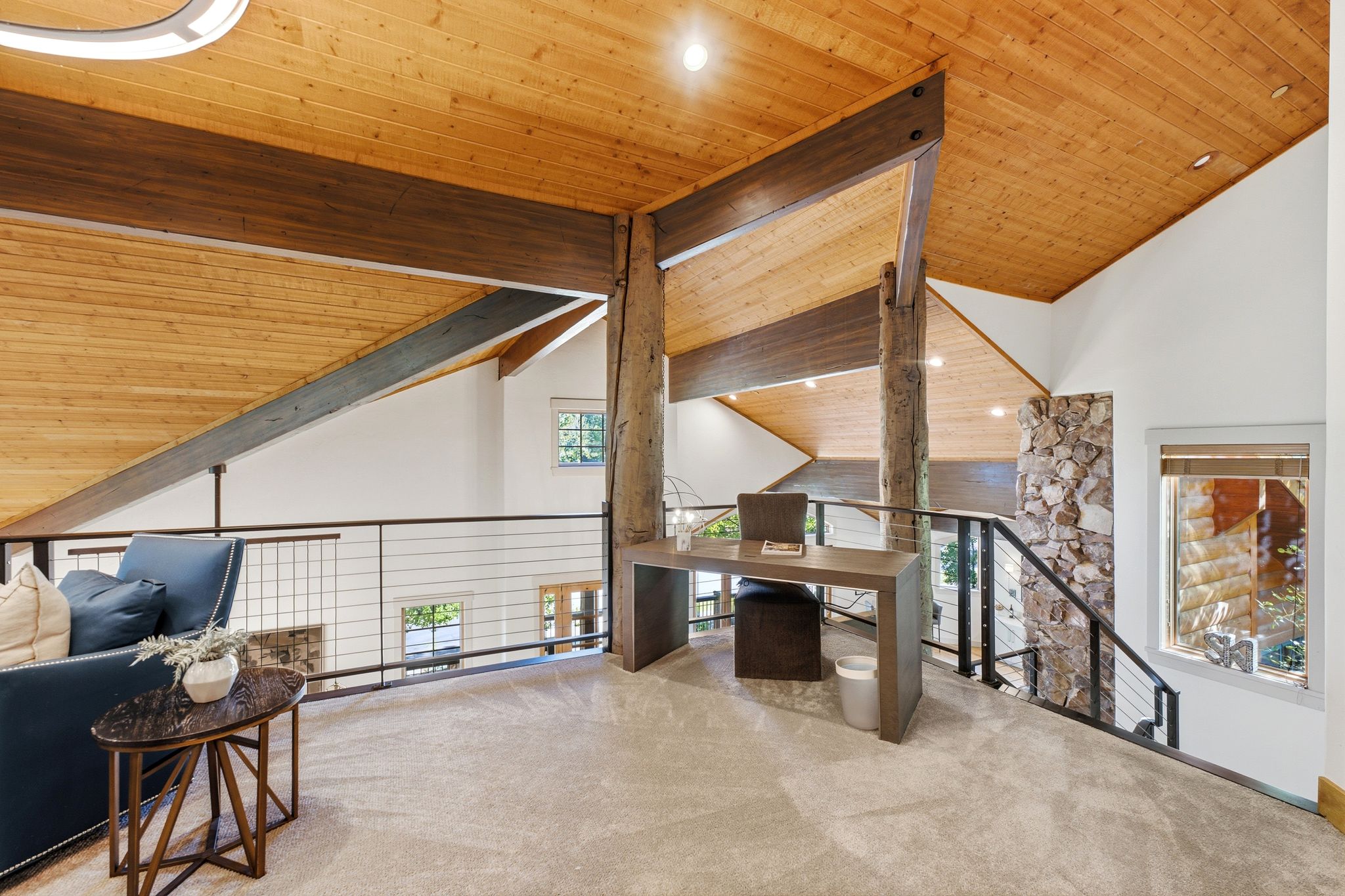 Loft area featuring vaulted wood-finish ceilings, exposed structural beams, and cable railing