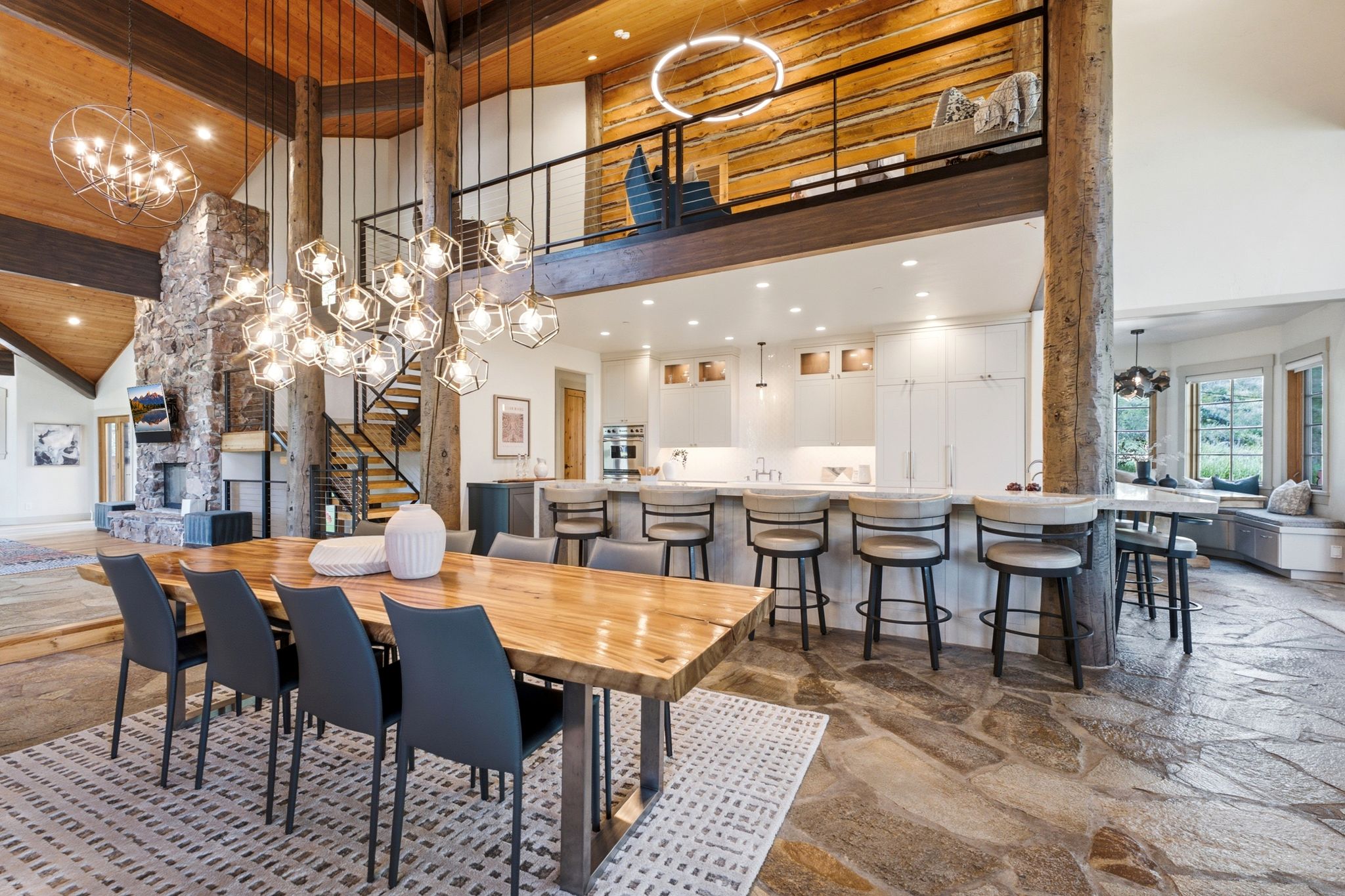 Open-concept living area featuring a vaulted wood-paneled ceiling, a stone-clad fireplace, and natural stone flooring