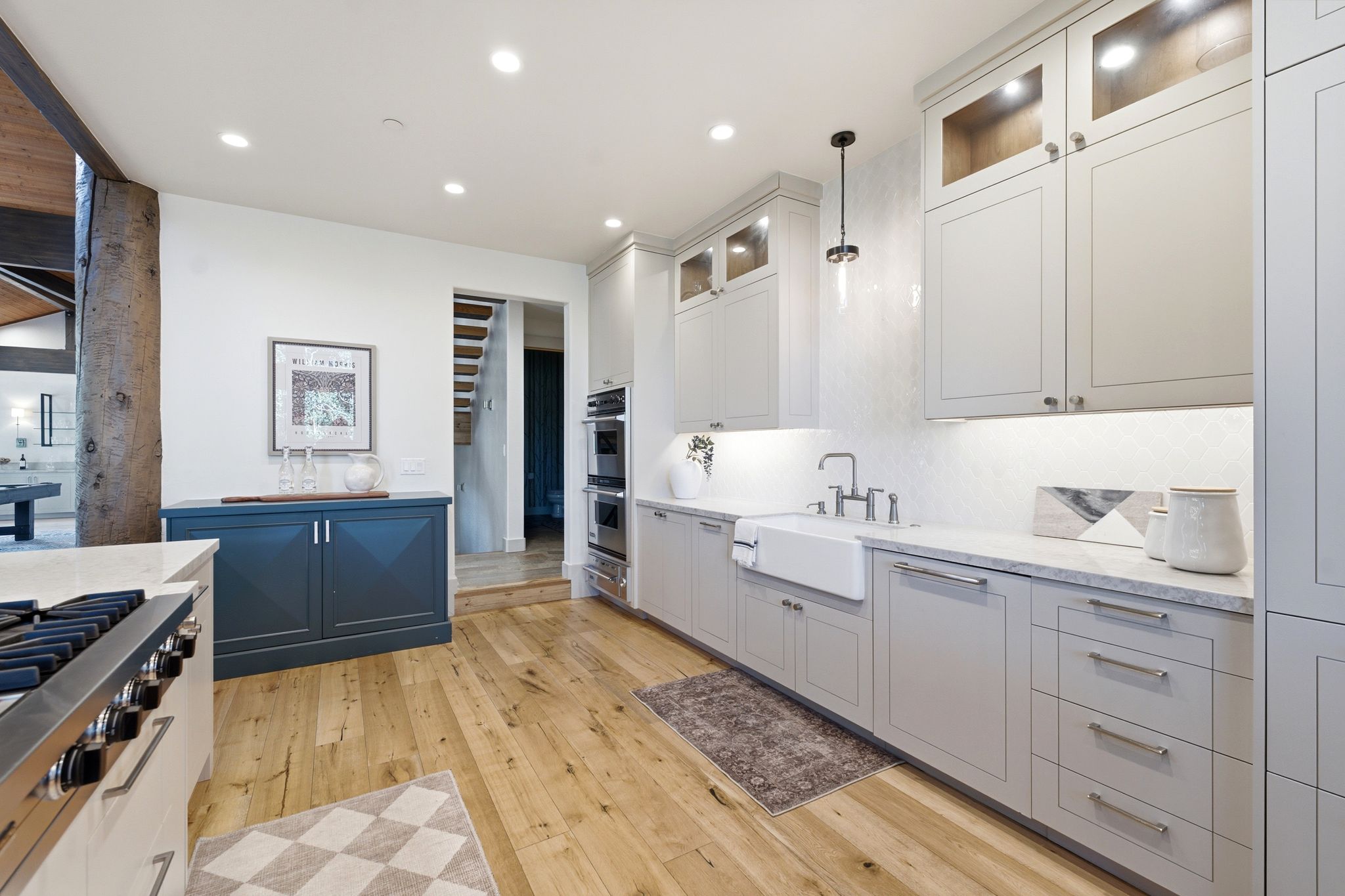 Modern kitchen featuring light wood-finish flooring, light grey cabinetry, and integrated double ovens