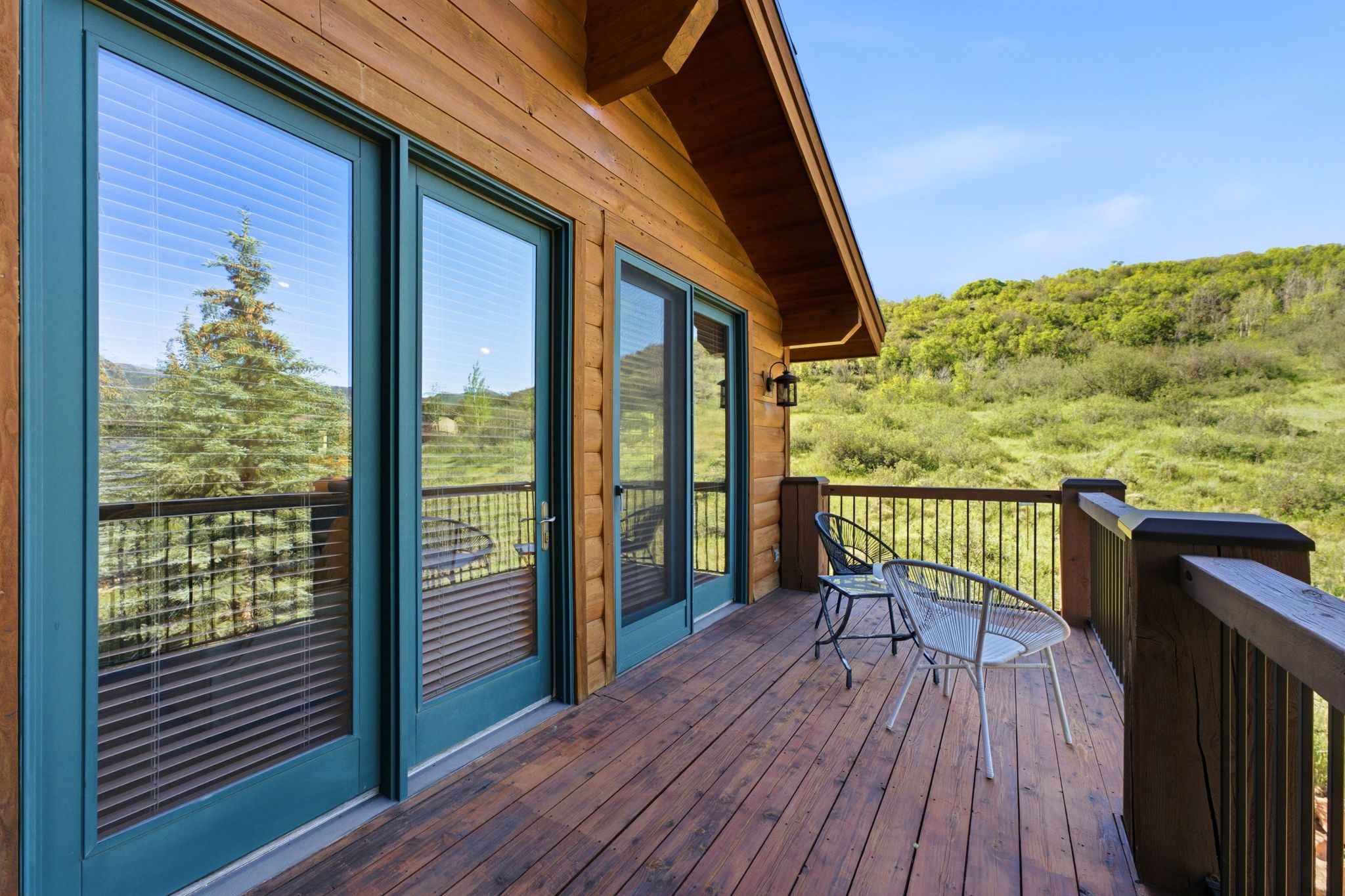 Expansive wood-finish deck with black metal railing and exterior lighting