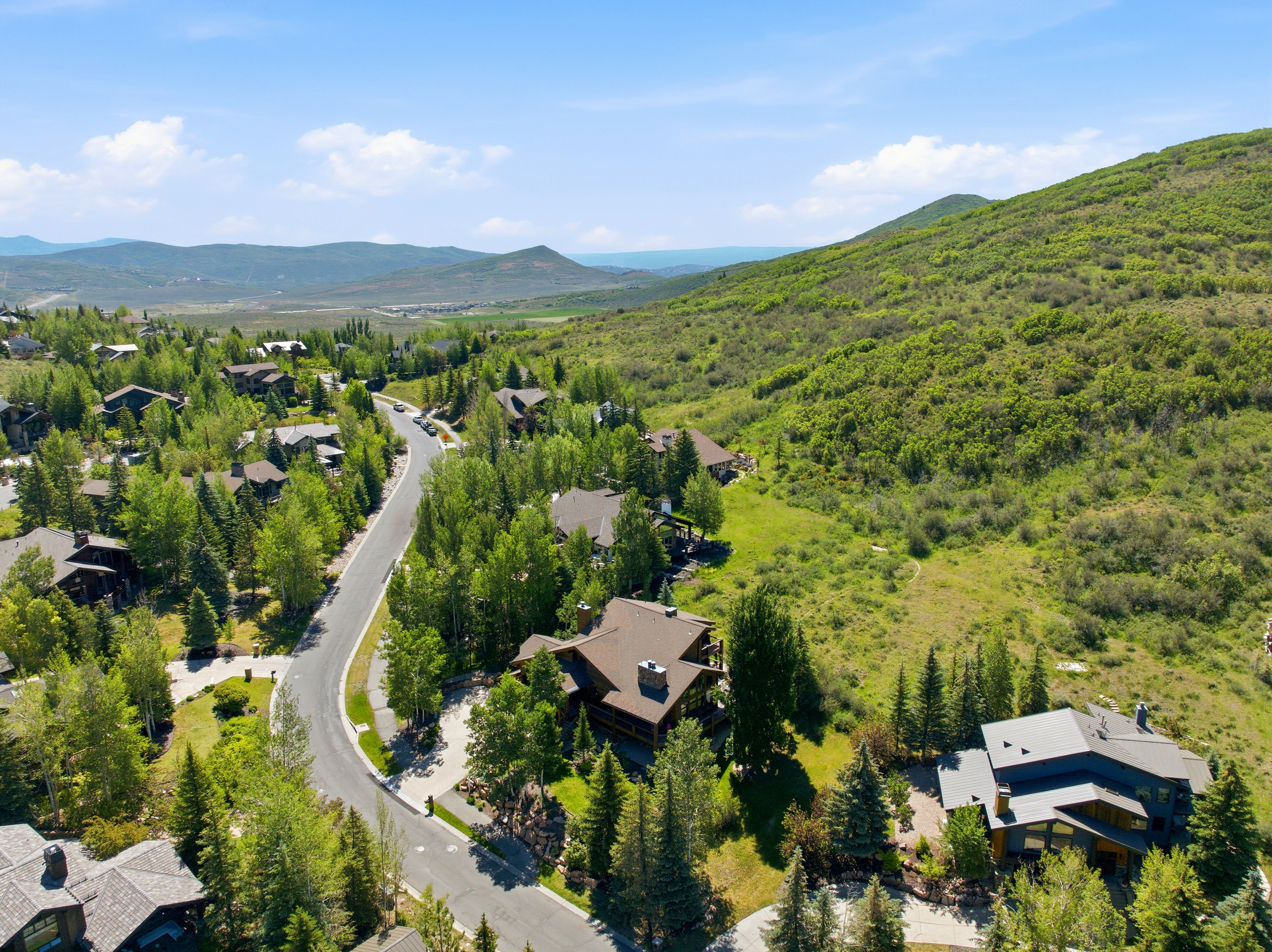 Mountainous terrain featuring a residential community with mature trees and paved roads