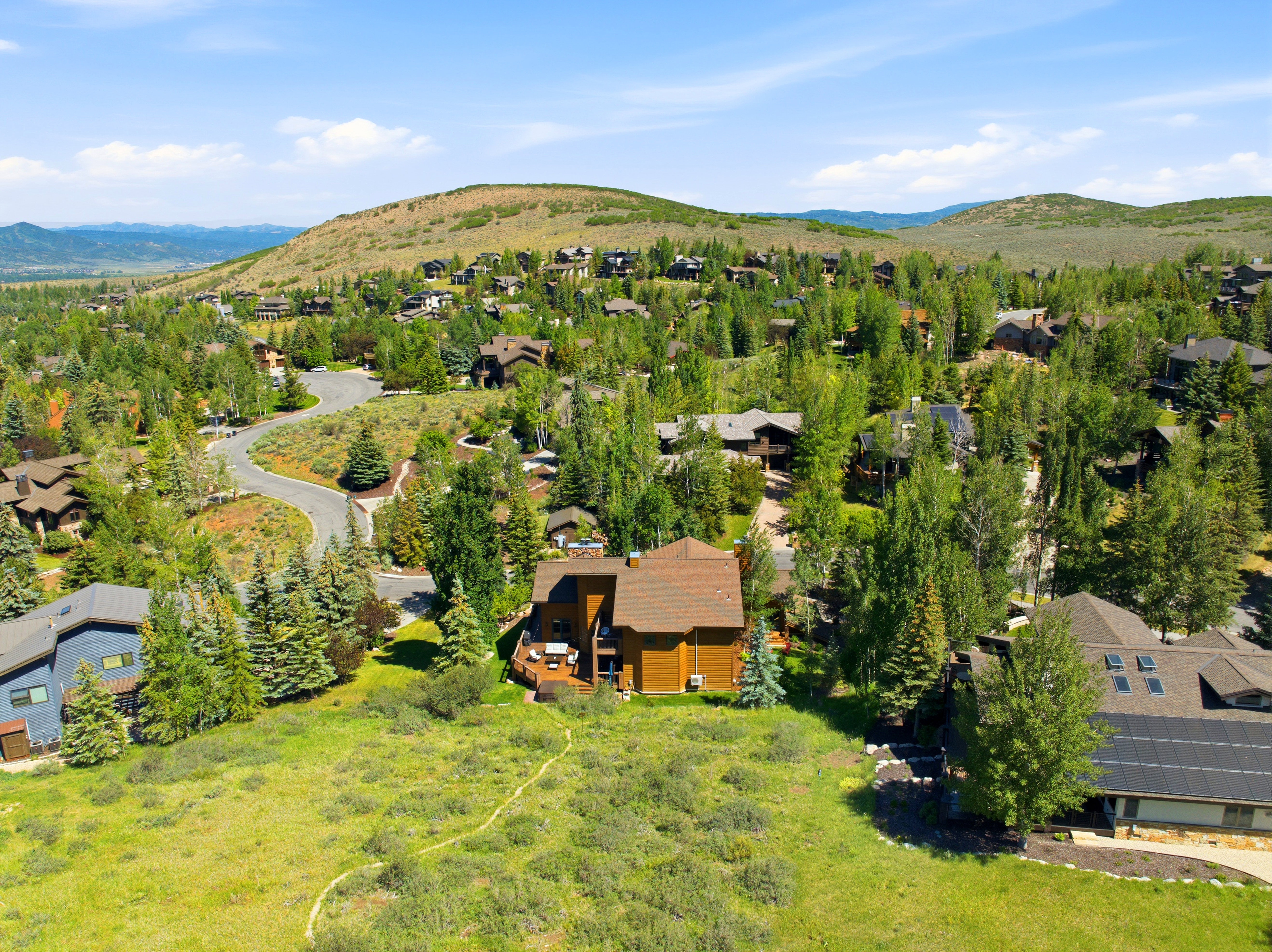 Rustic-style residence featuring a multi-level deck and surrounding mature trees